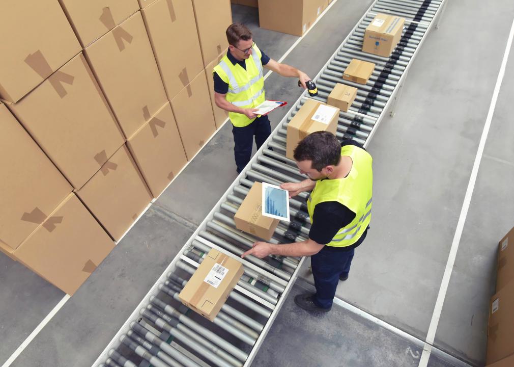 Two workers in a warehouse processing packages