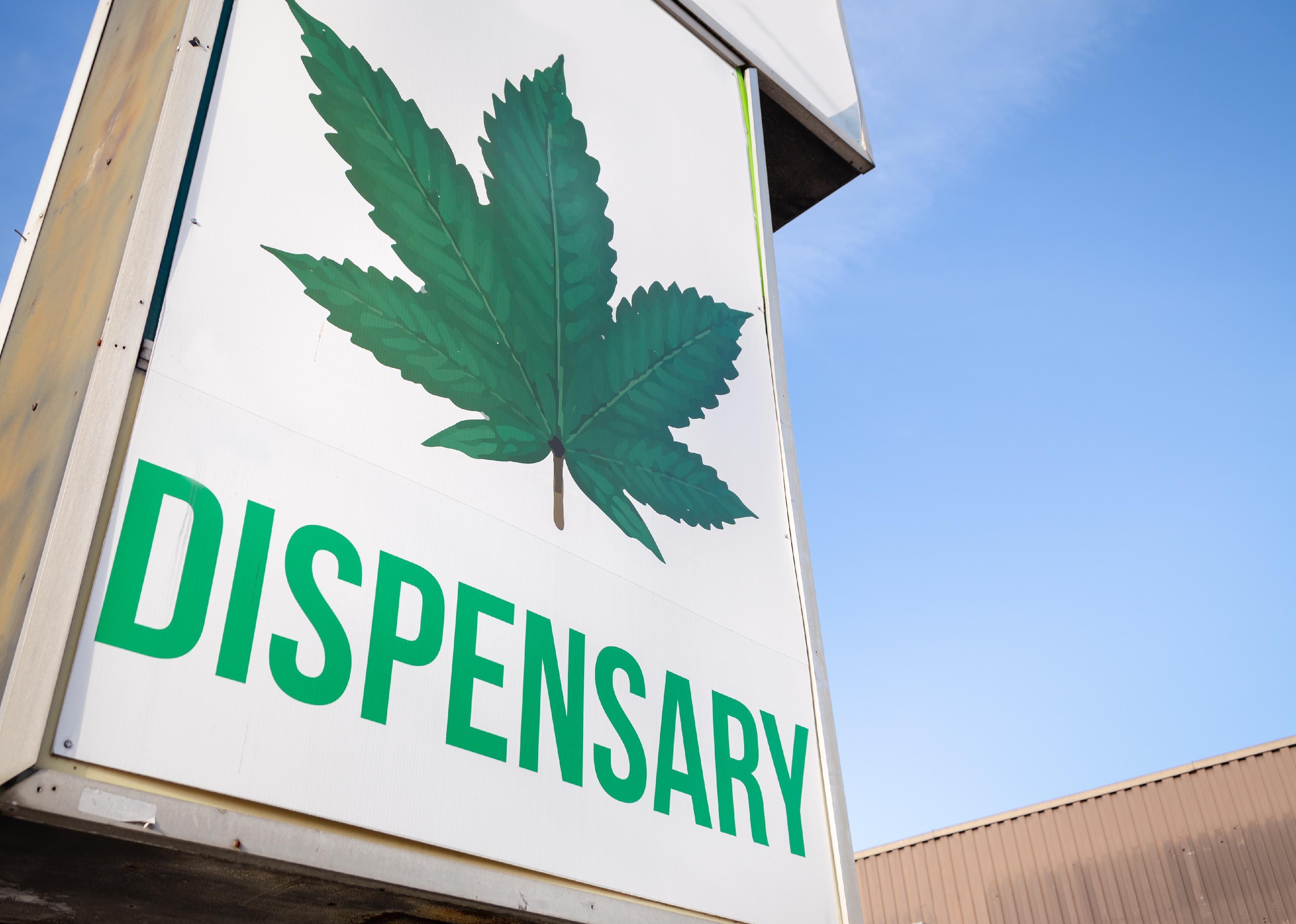 A cannabis dispensary sign with a large marijuana leaf on it.