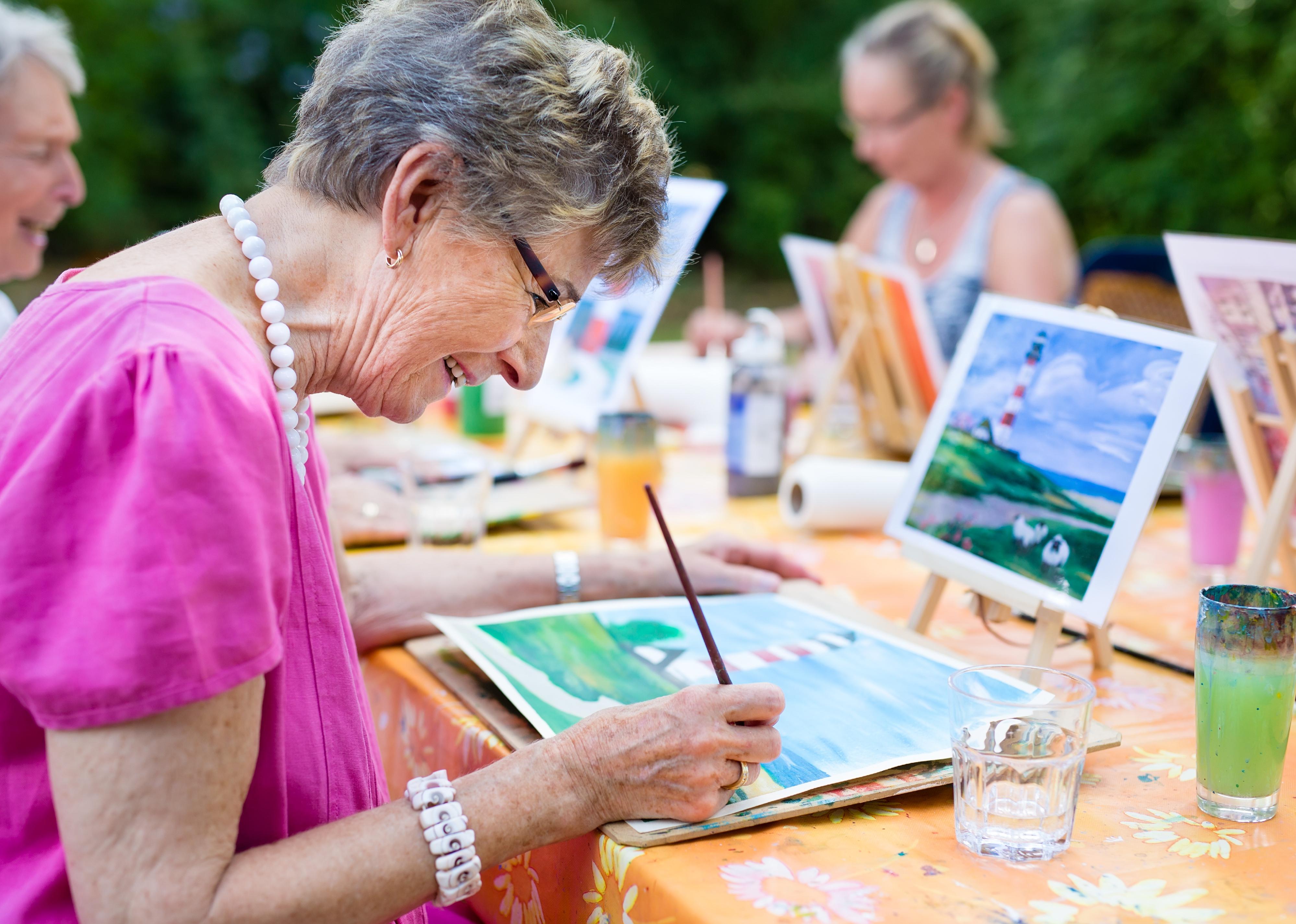 Side view of a happy senior smiling while painting.