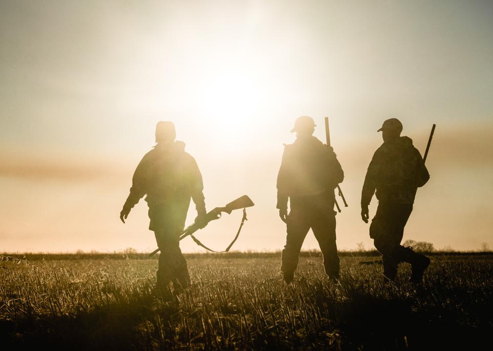 Three hunters walking into a sunset.