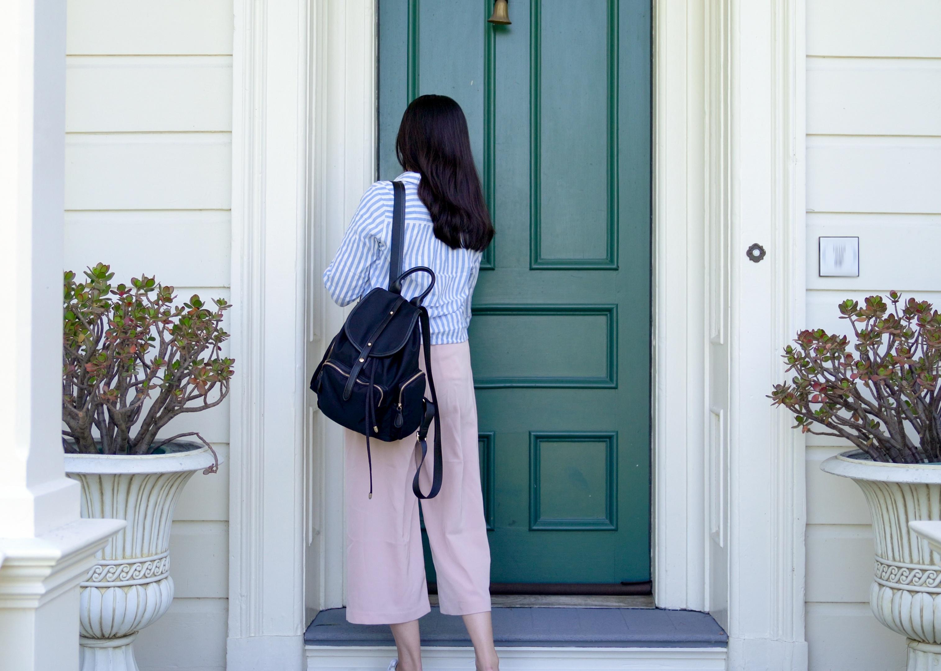 Back view of a woman using a key to open front door. 