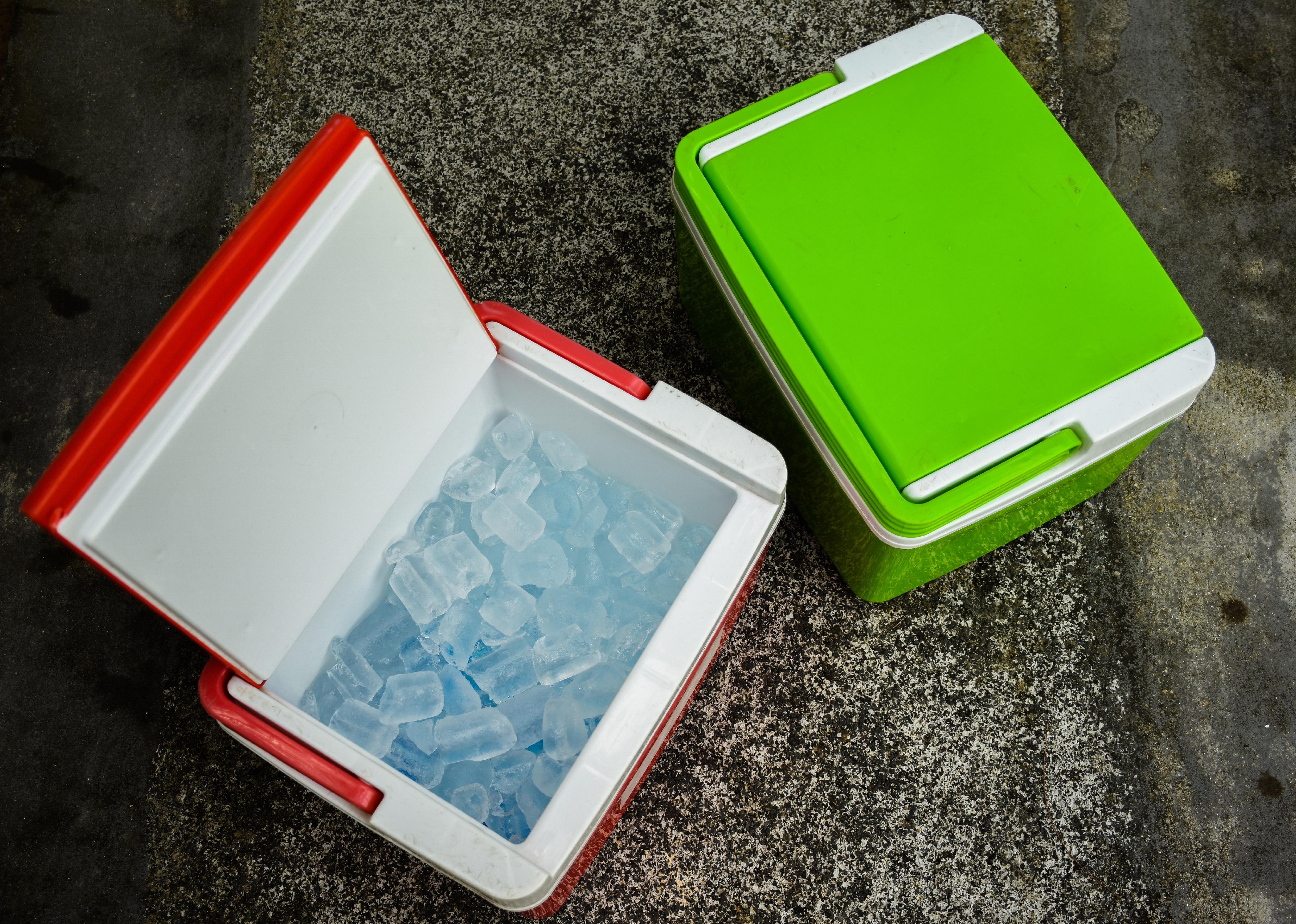 Top view of picnic cooler box with and ice cube on the ground