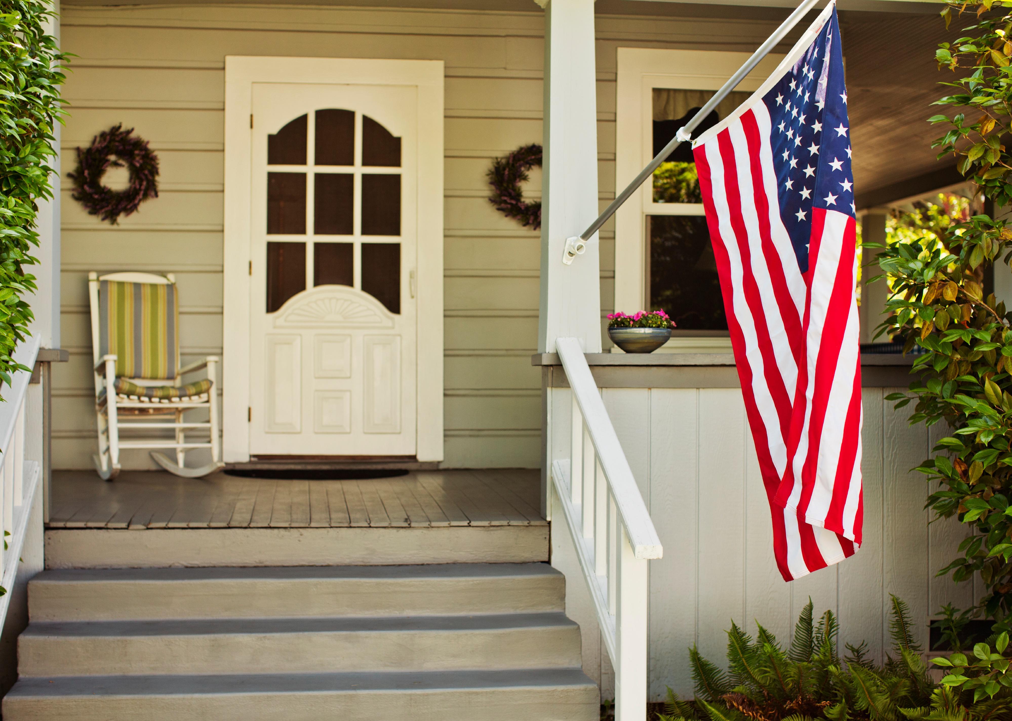 American flag hanging on the front porch of a suburban house
