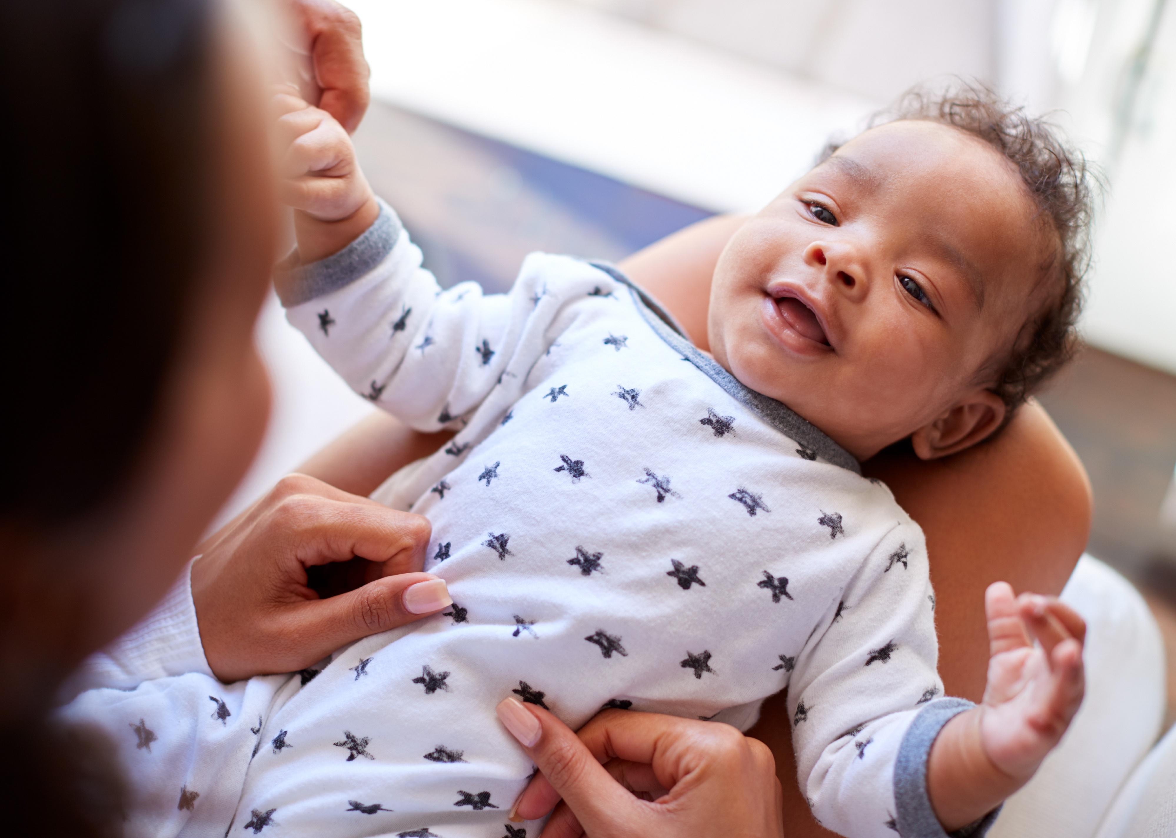 Smiling baby laying on his back on woman's lap.