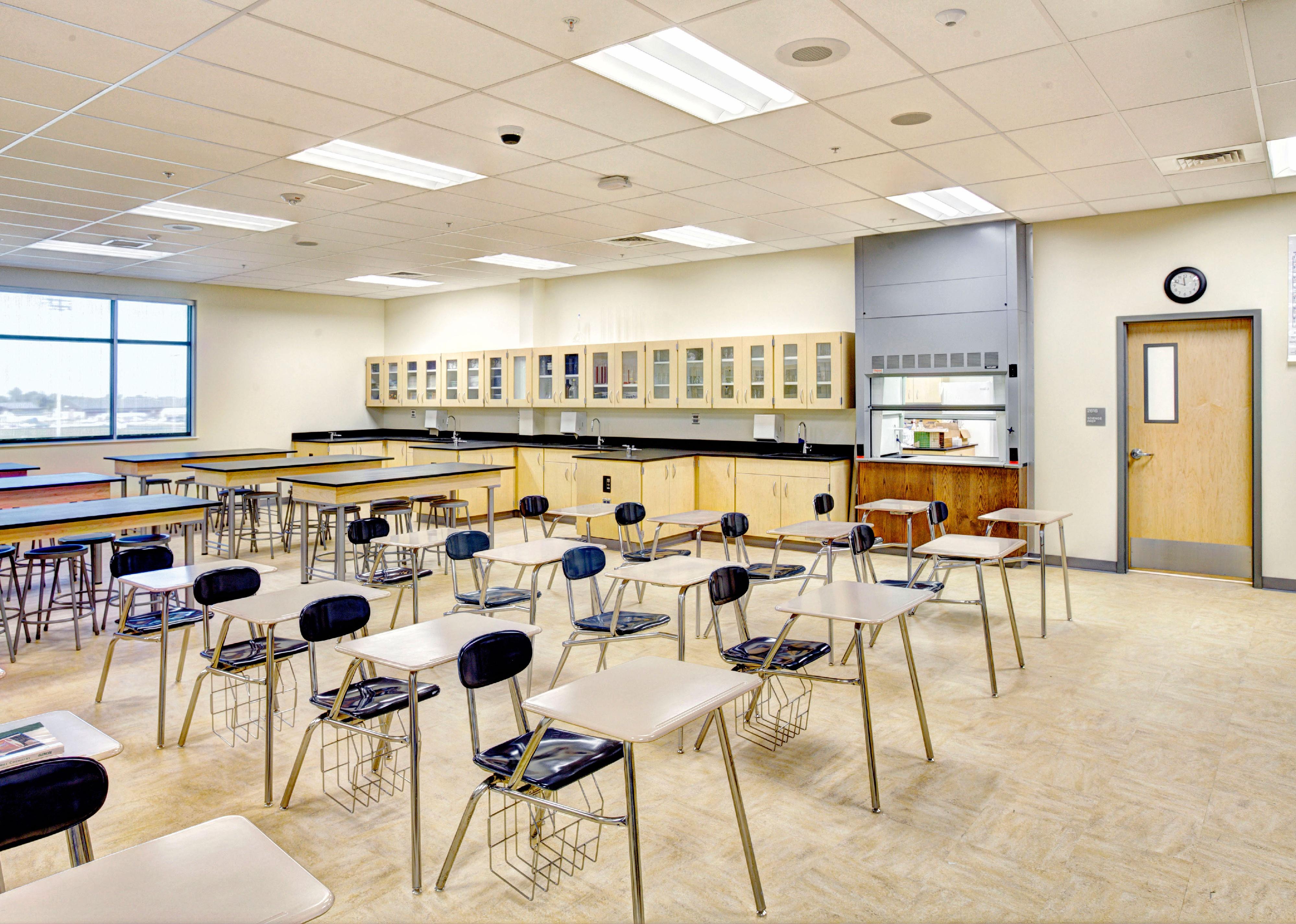 Science classroom with desks, tables, lab area, and biology models