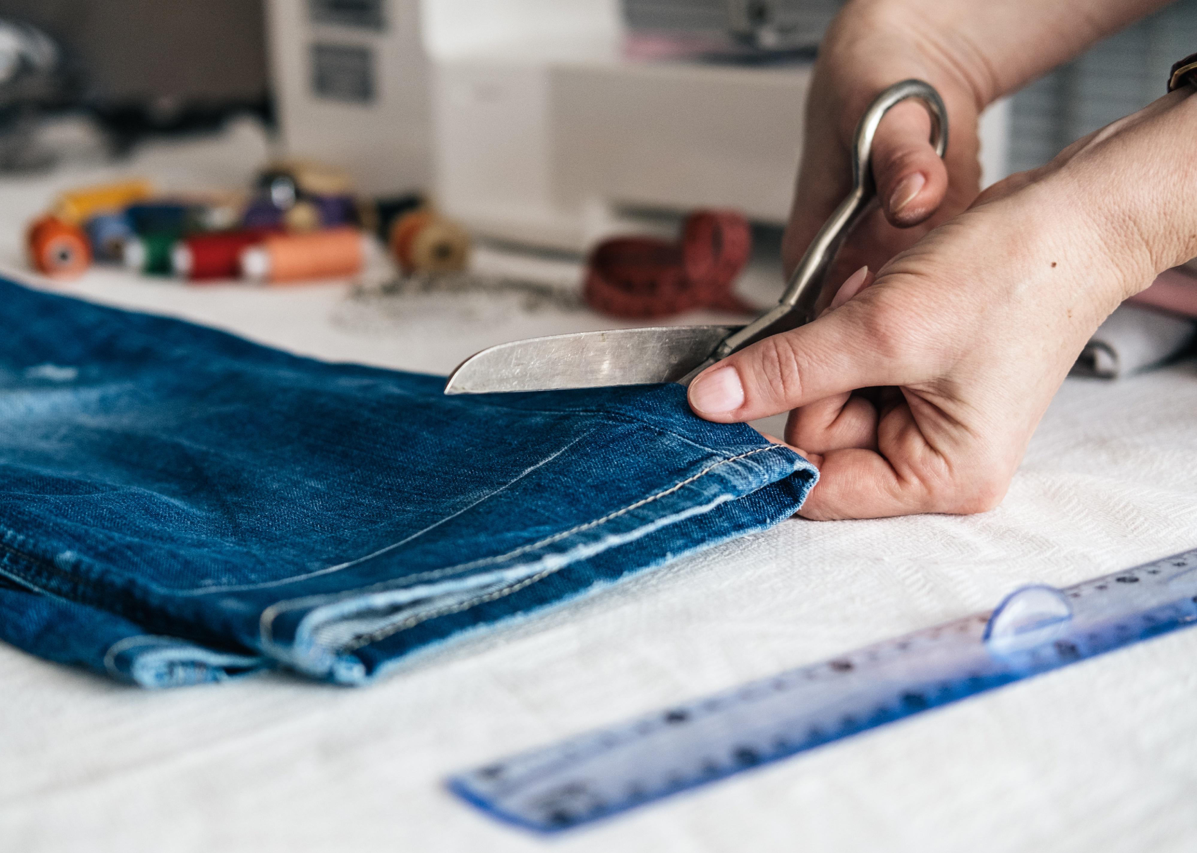 Image of hand cutting jeans.