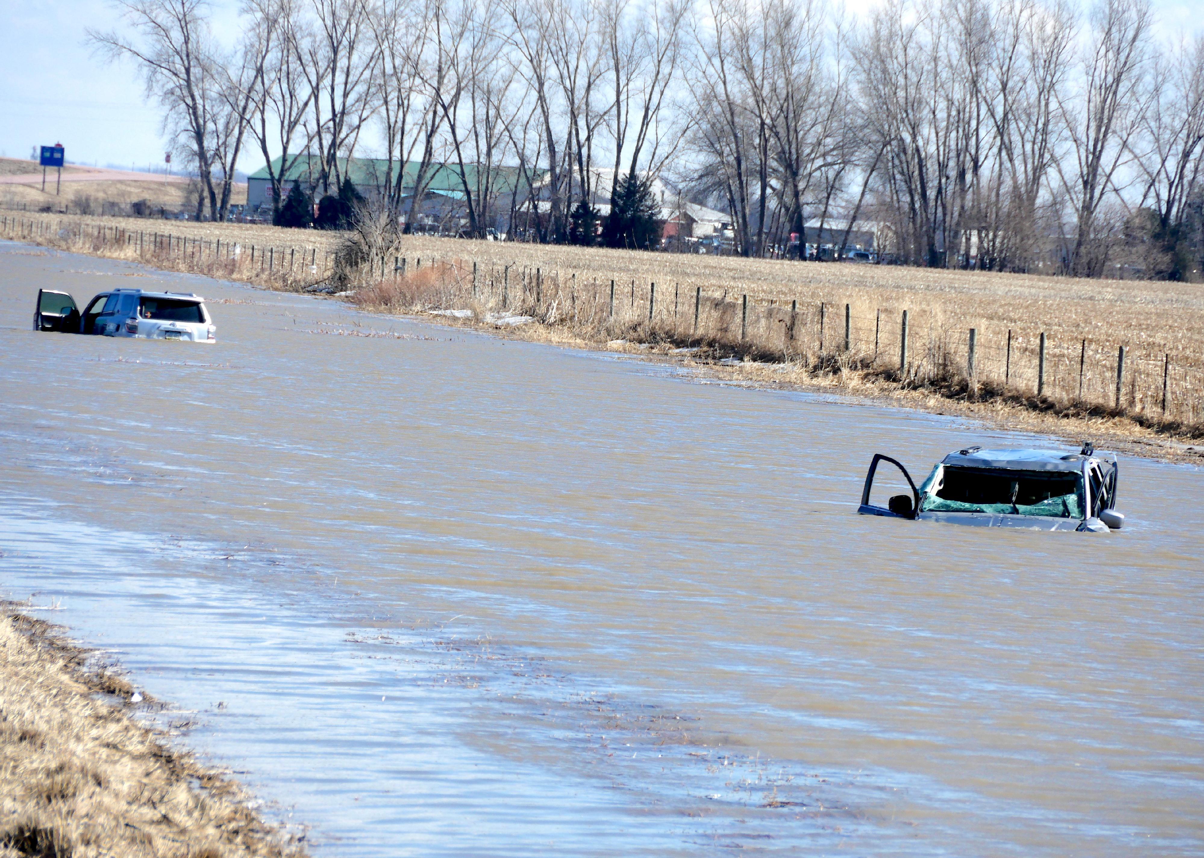 Two cars completely submerged in water next to South Dakota I-29.