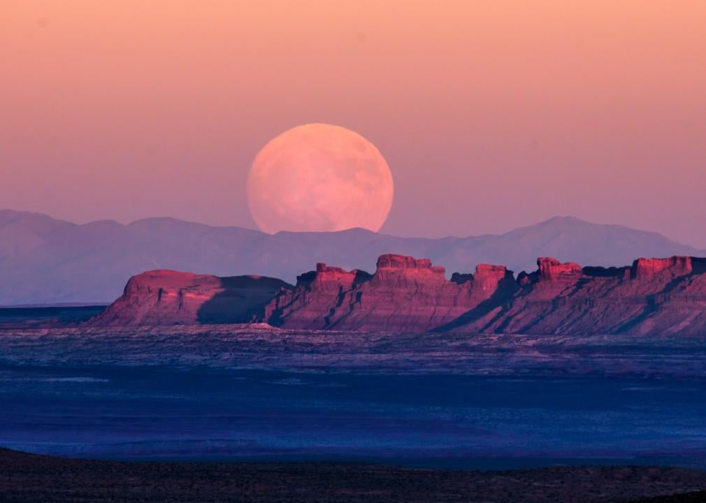A supermoon rises over Monument Valley.