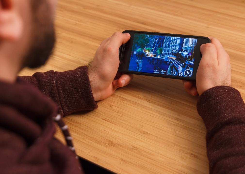 Man holding a smartphone and playng the Sniper 3D mobile game.