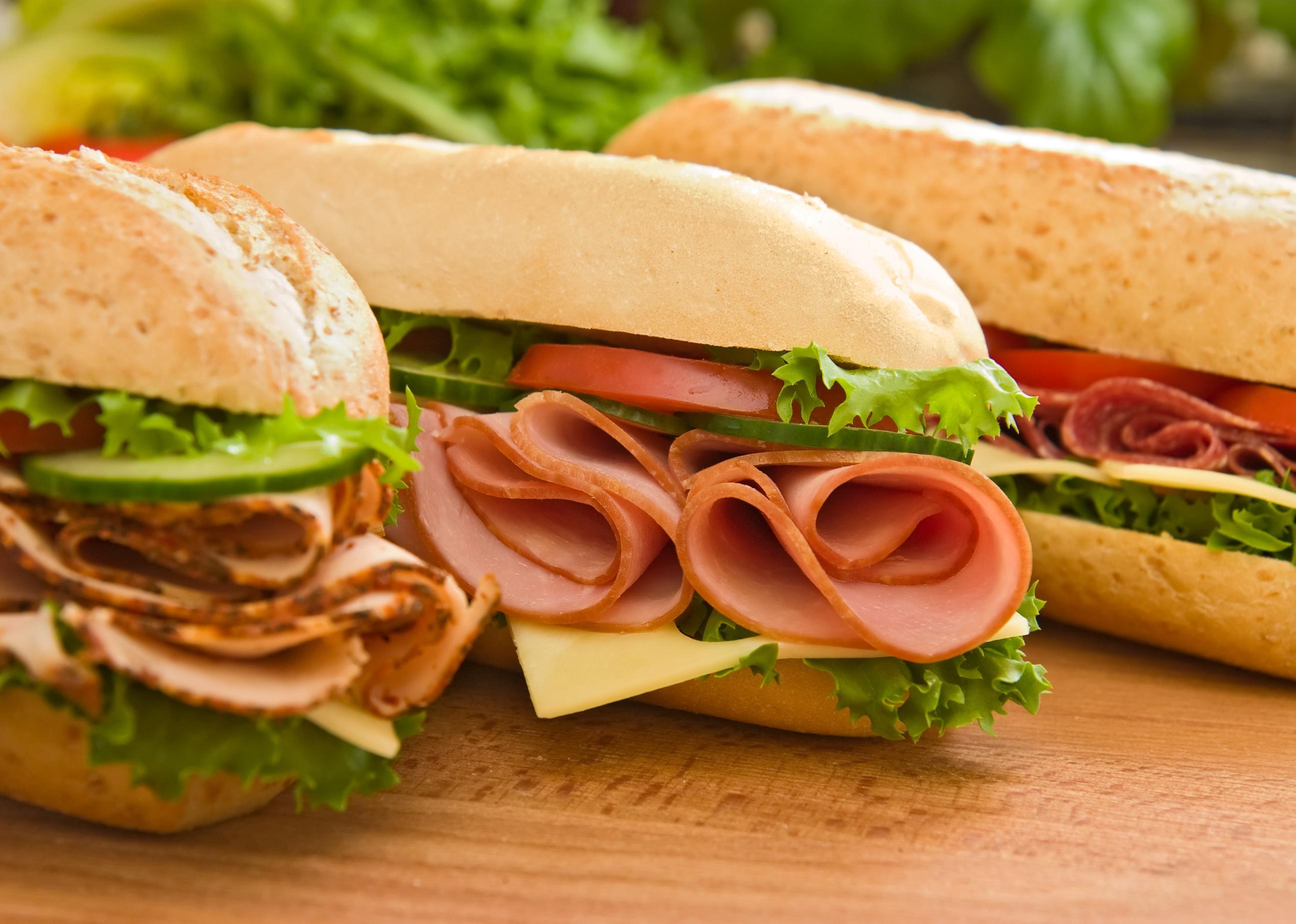 Three fresh sandwiches on a cutting board.