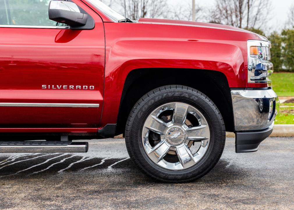 A side picture of a red and rain covered 2017 Chevrolet Silverado.