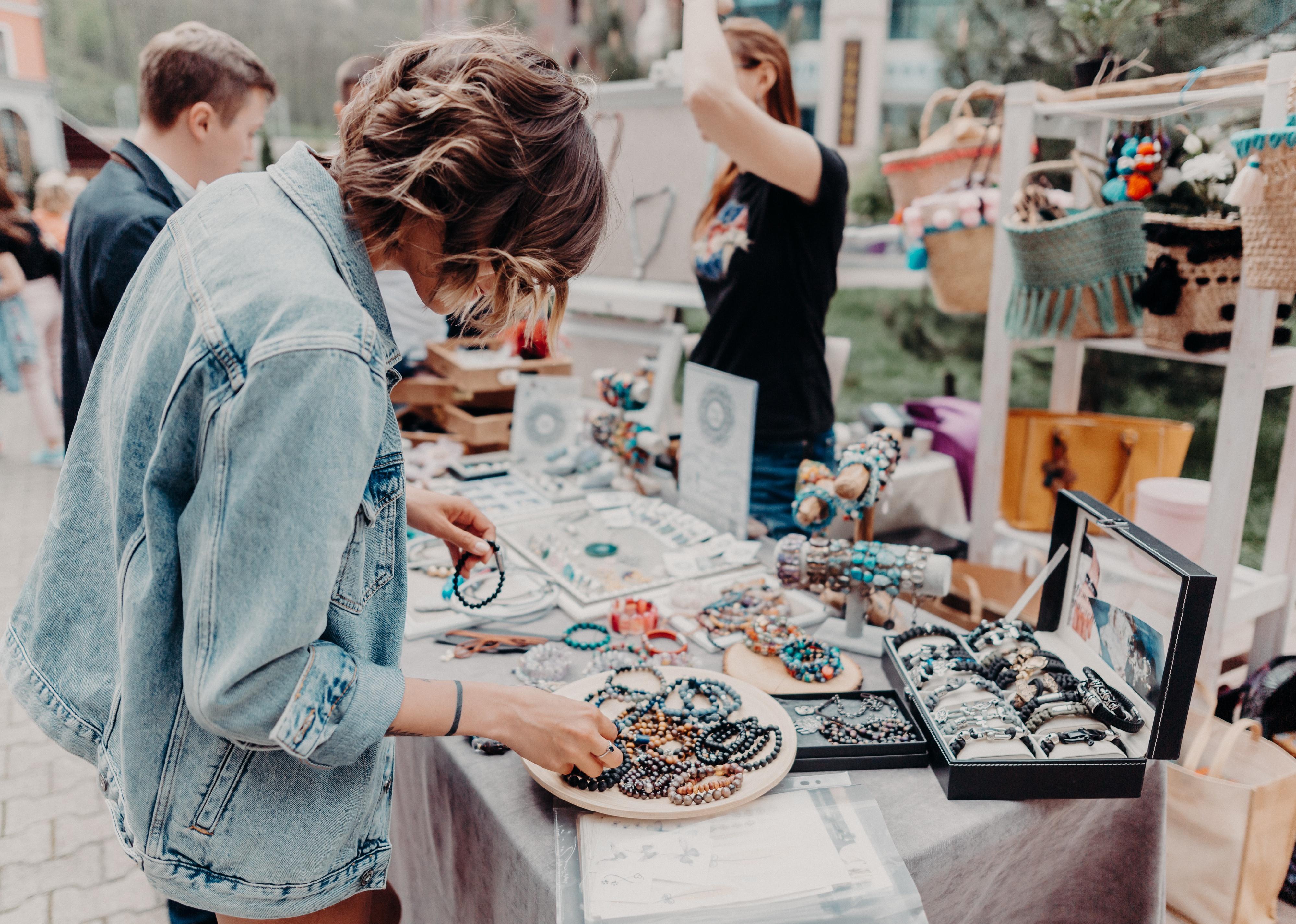 Girl looking at the colourful handmade jewelry on the local fair outside. 