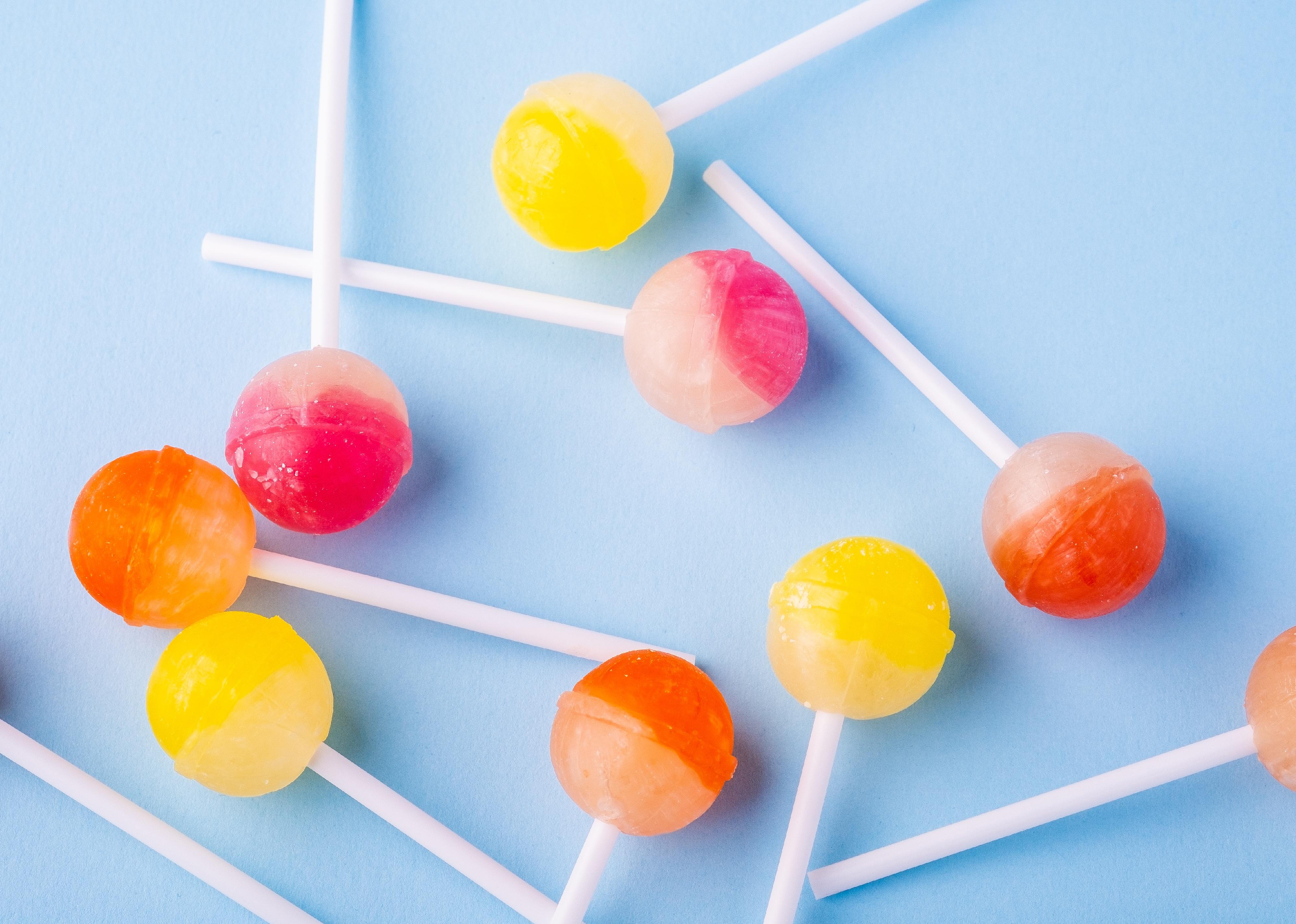 Scattered lollipop candies on blue background top view.