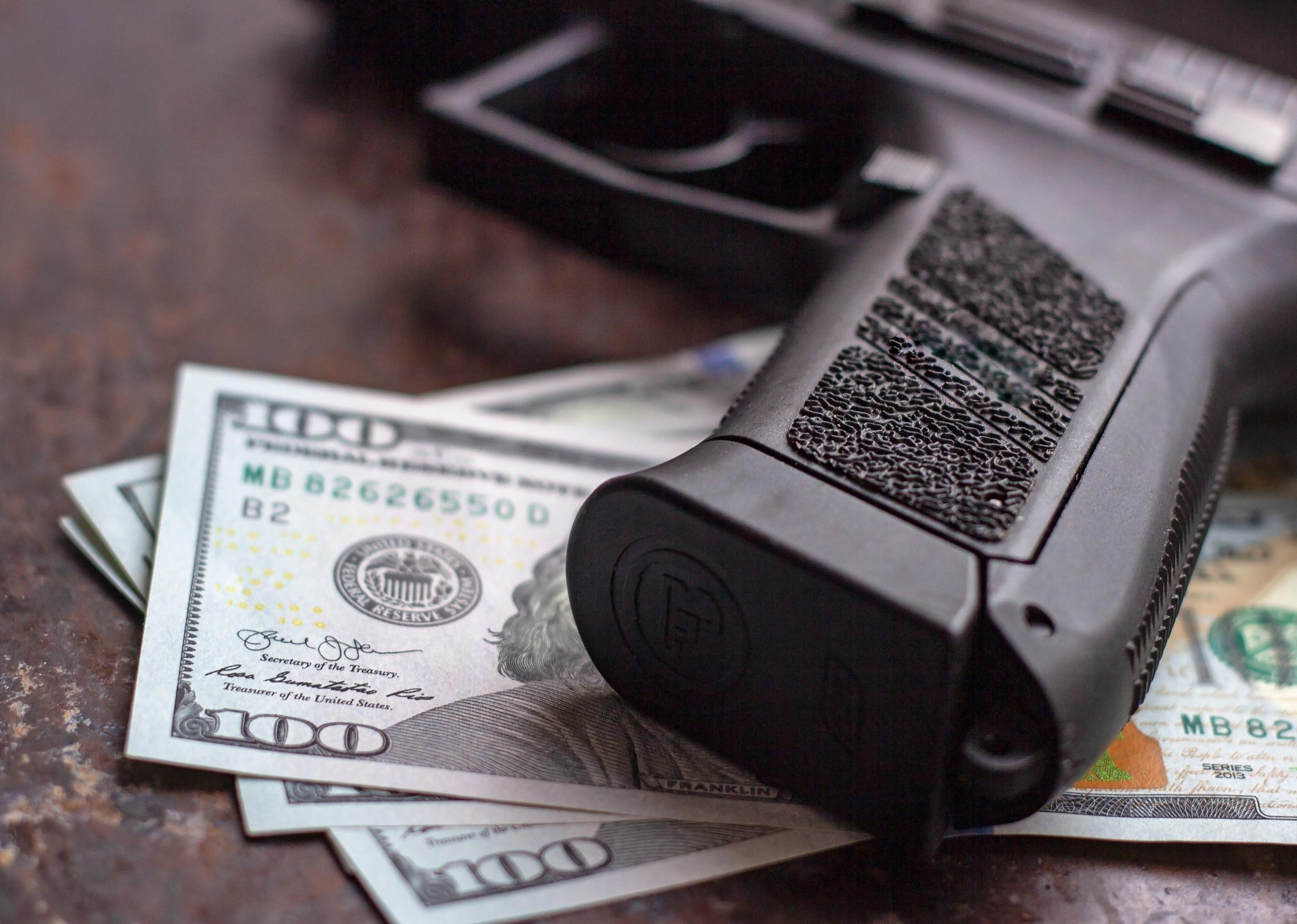 Gun sitting atop 100 dollar bills.