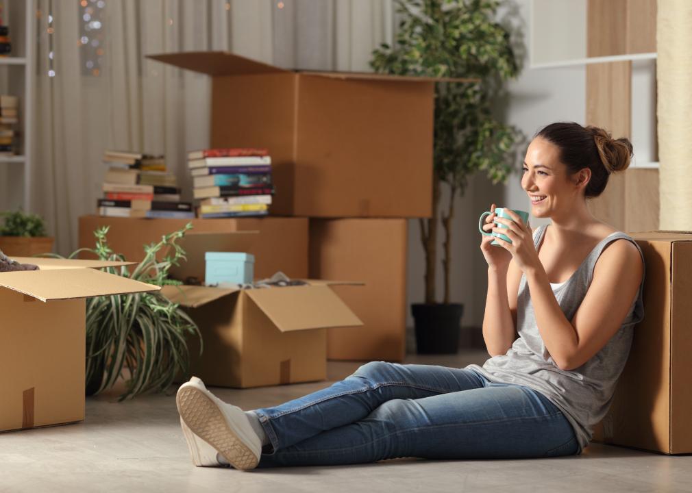 Smiling woman sitting on floor surrounded by moving boxes