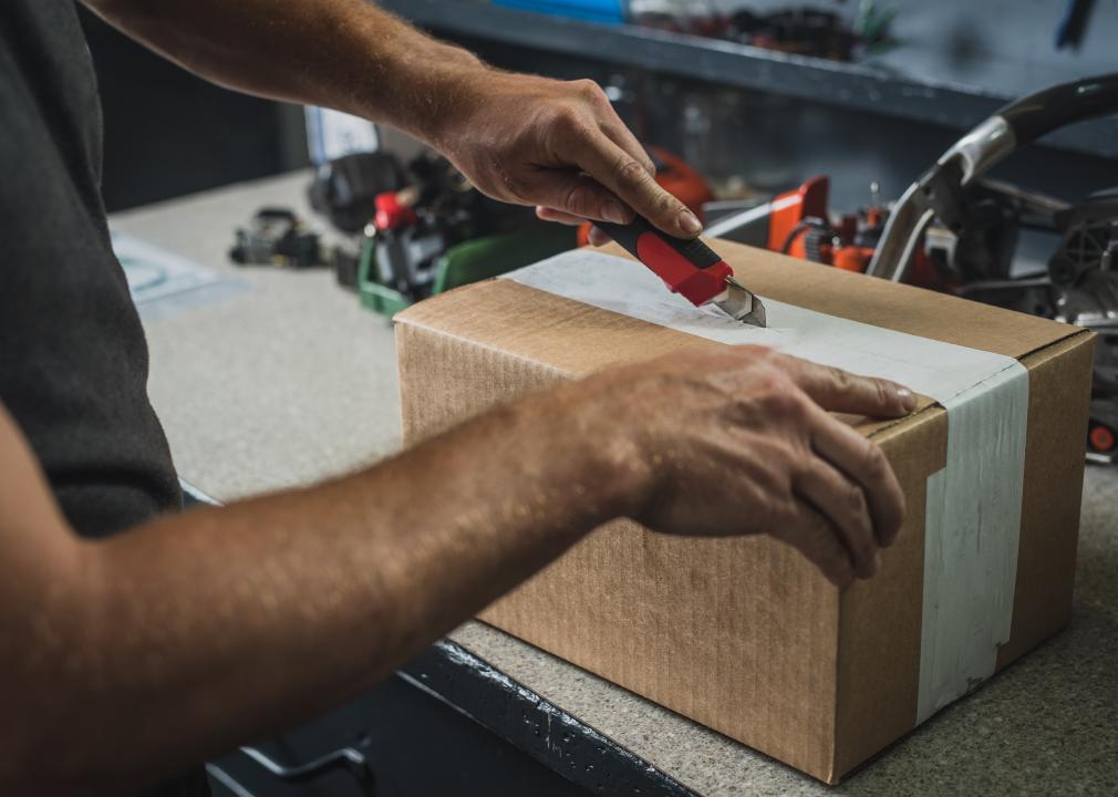 Man opening a cardboard box using a utility knife