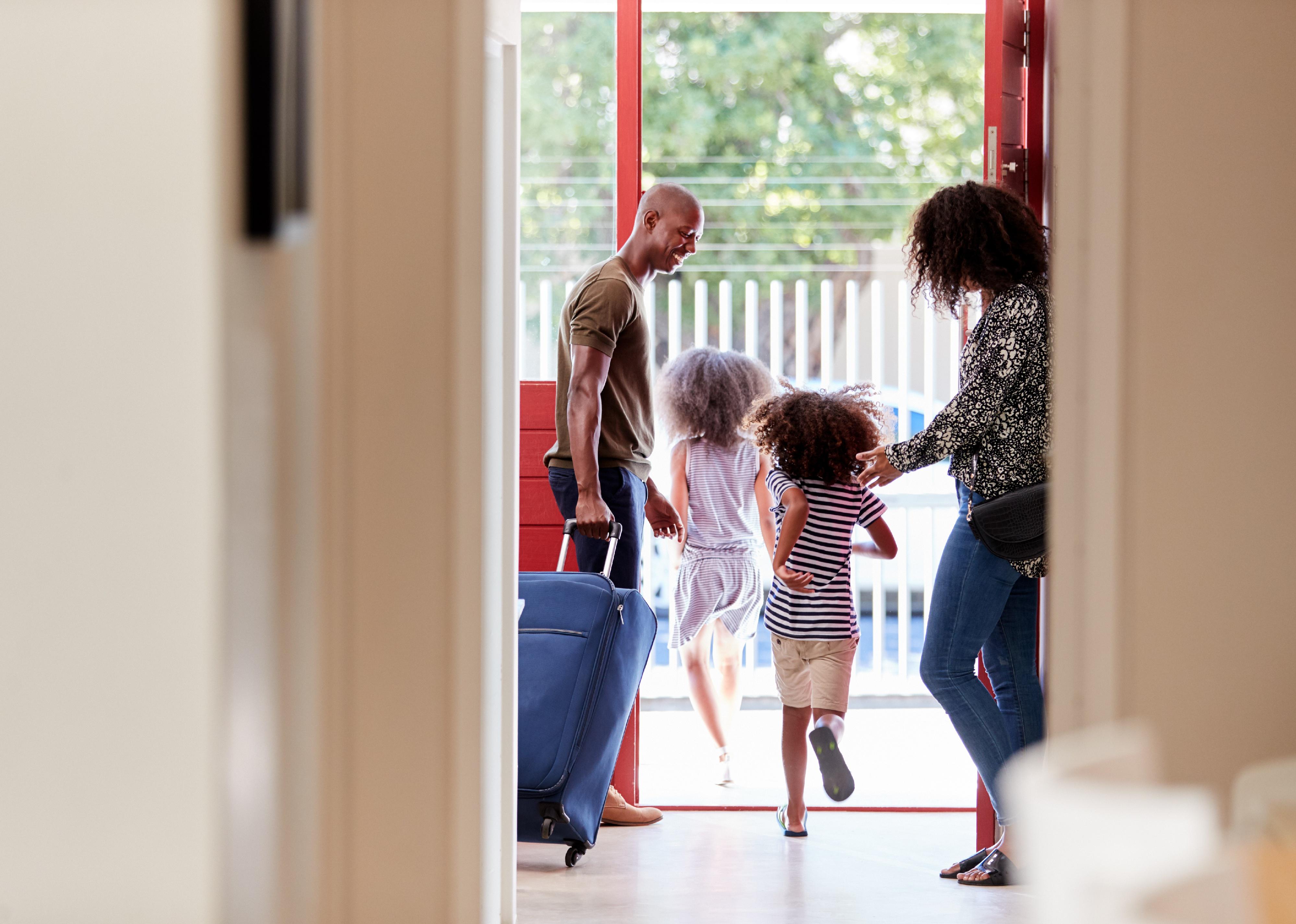 Family by front door with suitcase about to leave.