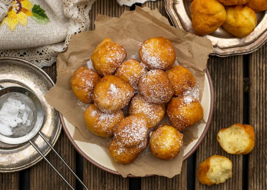 Plate of homemade deep fried fritters with powdered sugar.