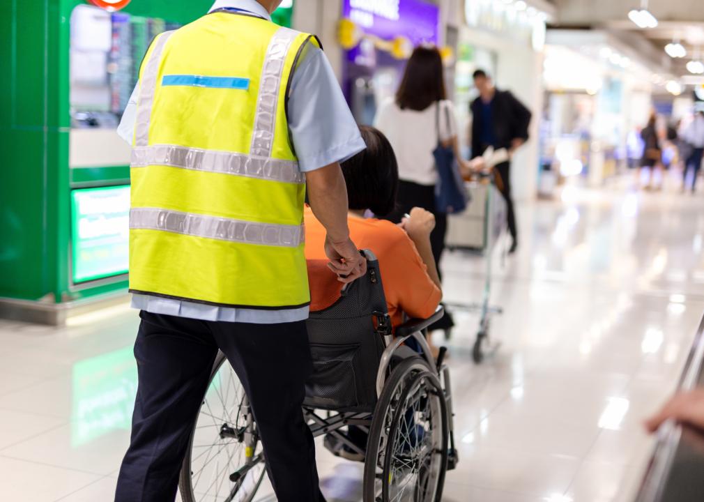 Caretaker pushes an elderly woman on a wheelchair in airport terminal