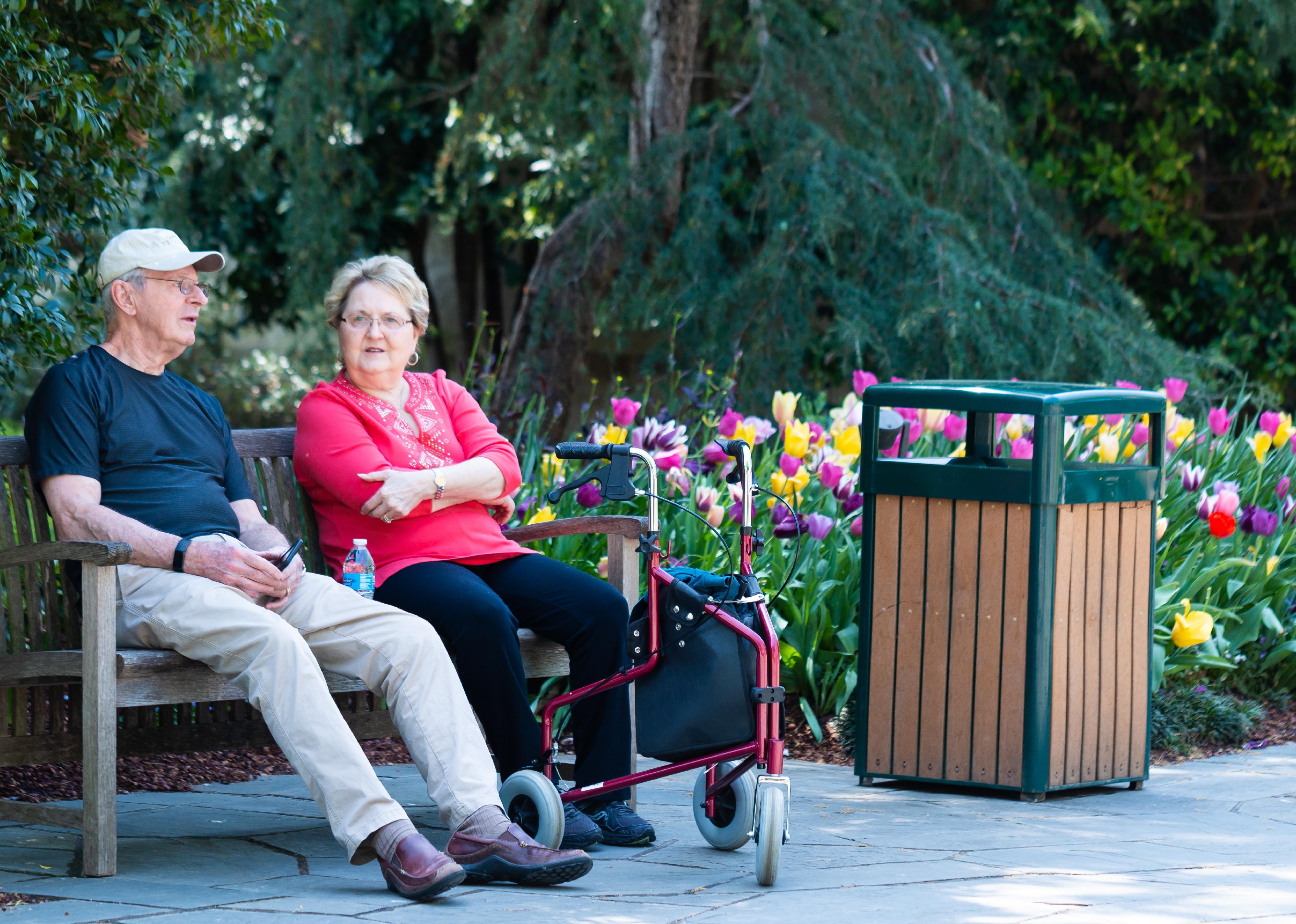 Man and woman with a walker witting on a bench.