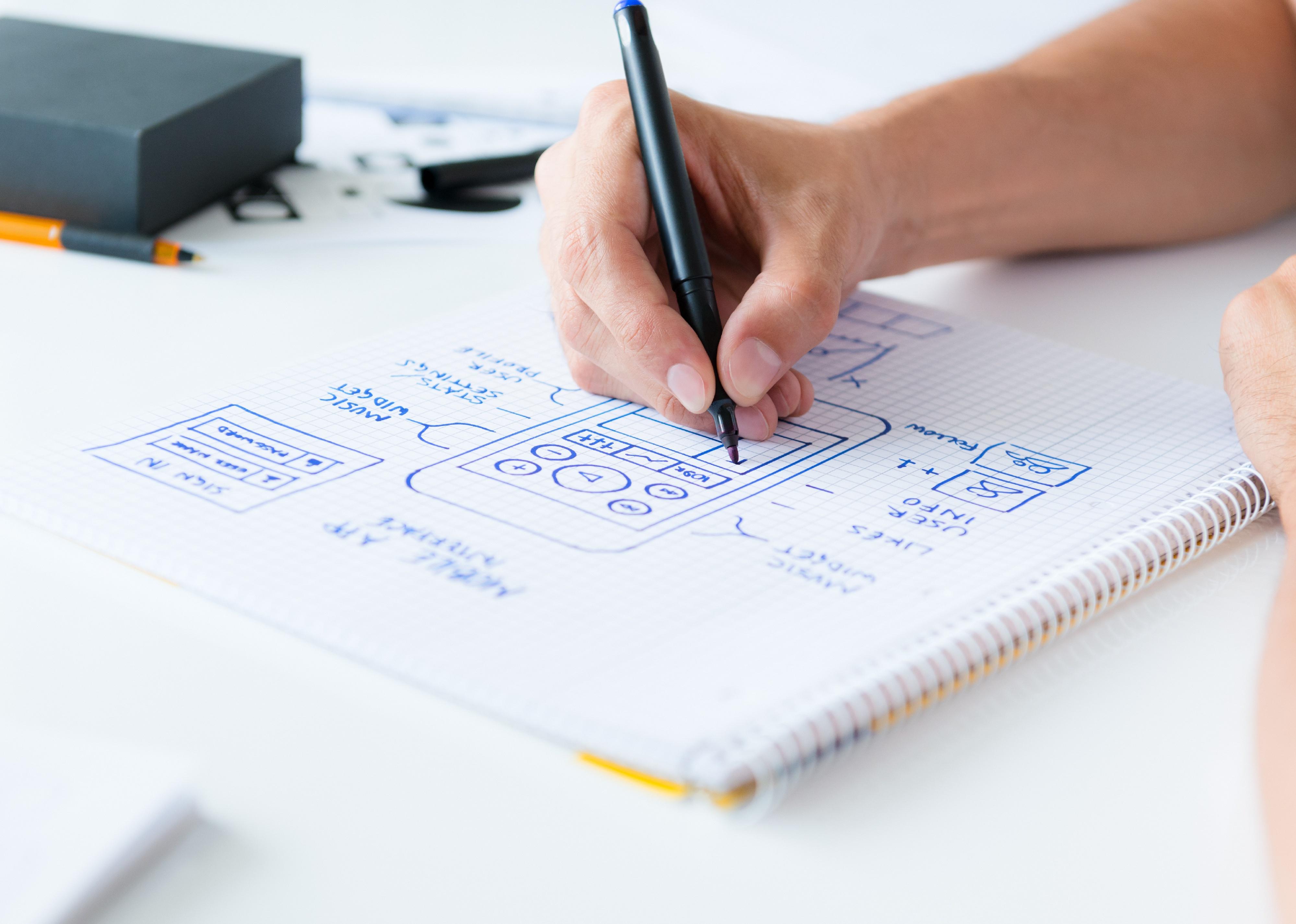 Designer drawing app framework on a paper.