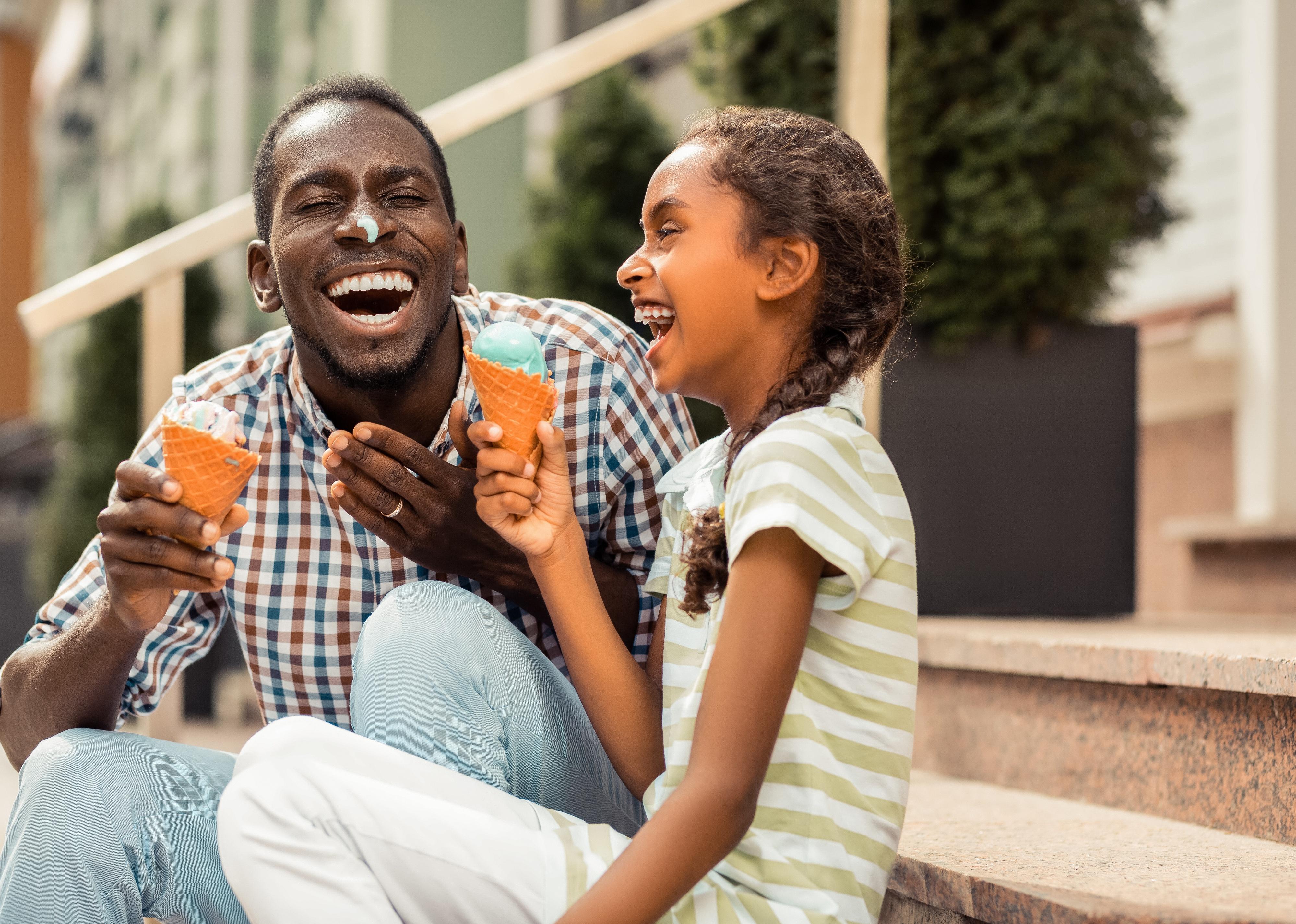 Young man and little girl laughing with ice cream.