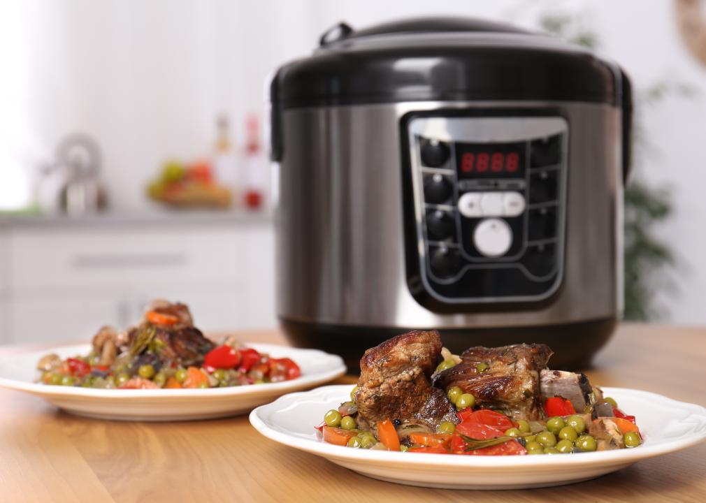 Plates with meat and garnish prepared in multi cooker