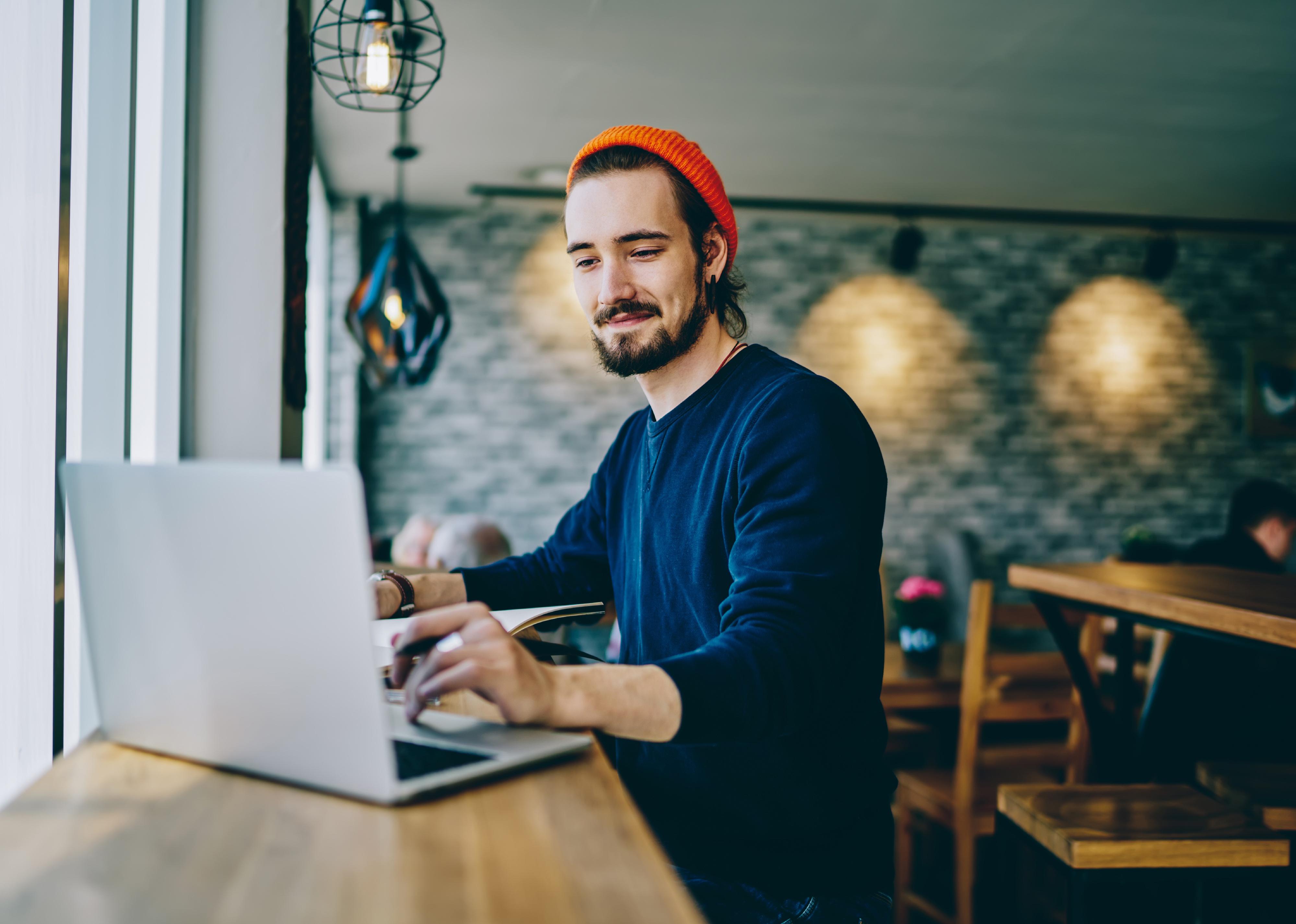 Man looking on screen of laptop computer in a coffee shop.