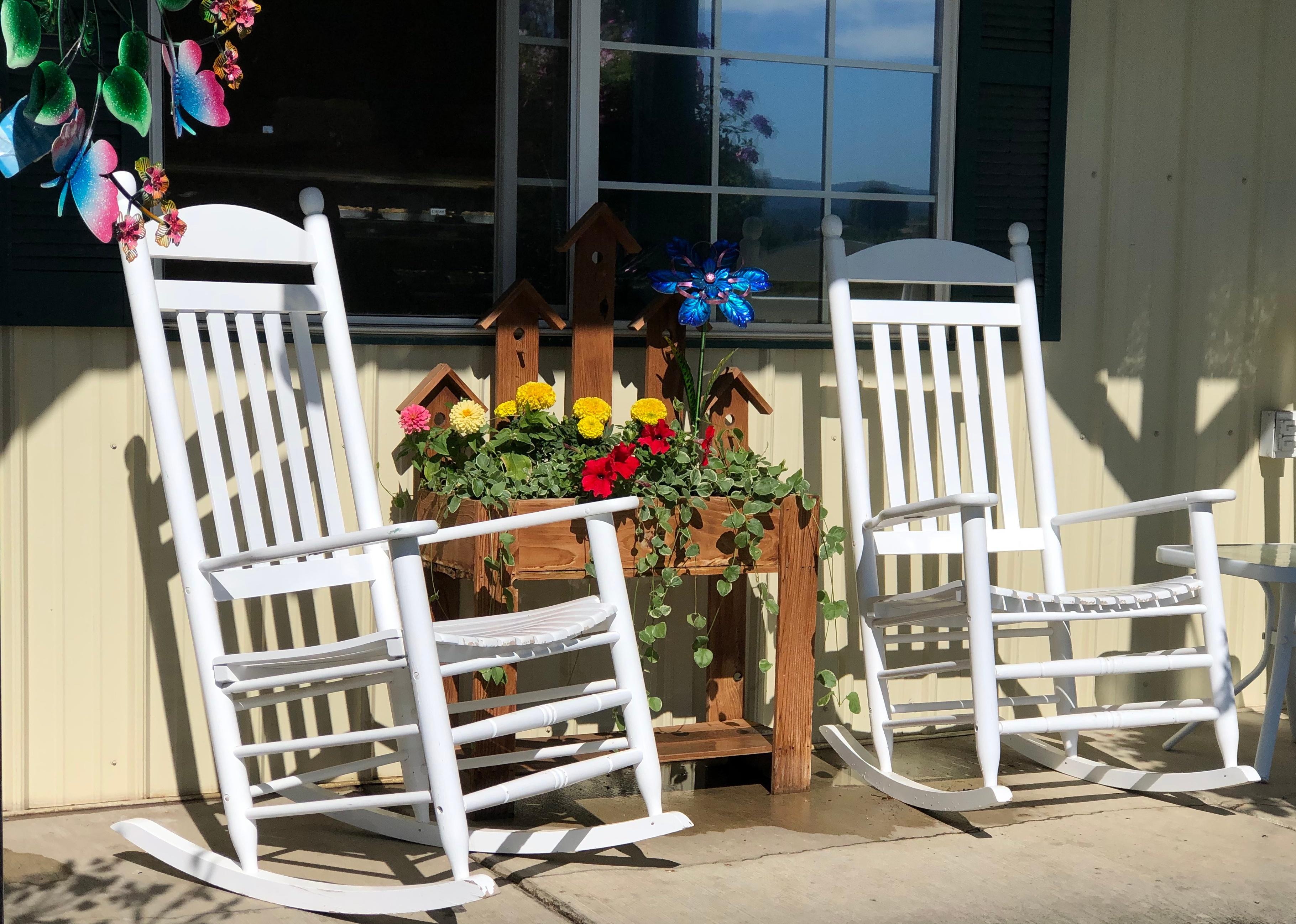 Front porch seating with white rocking chairs and fresh flowers.