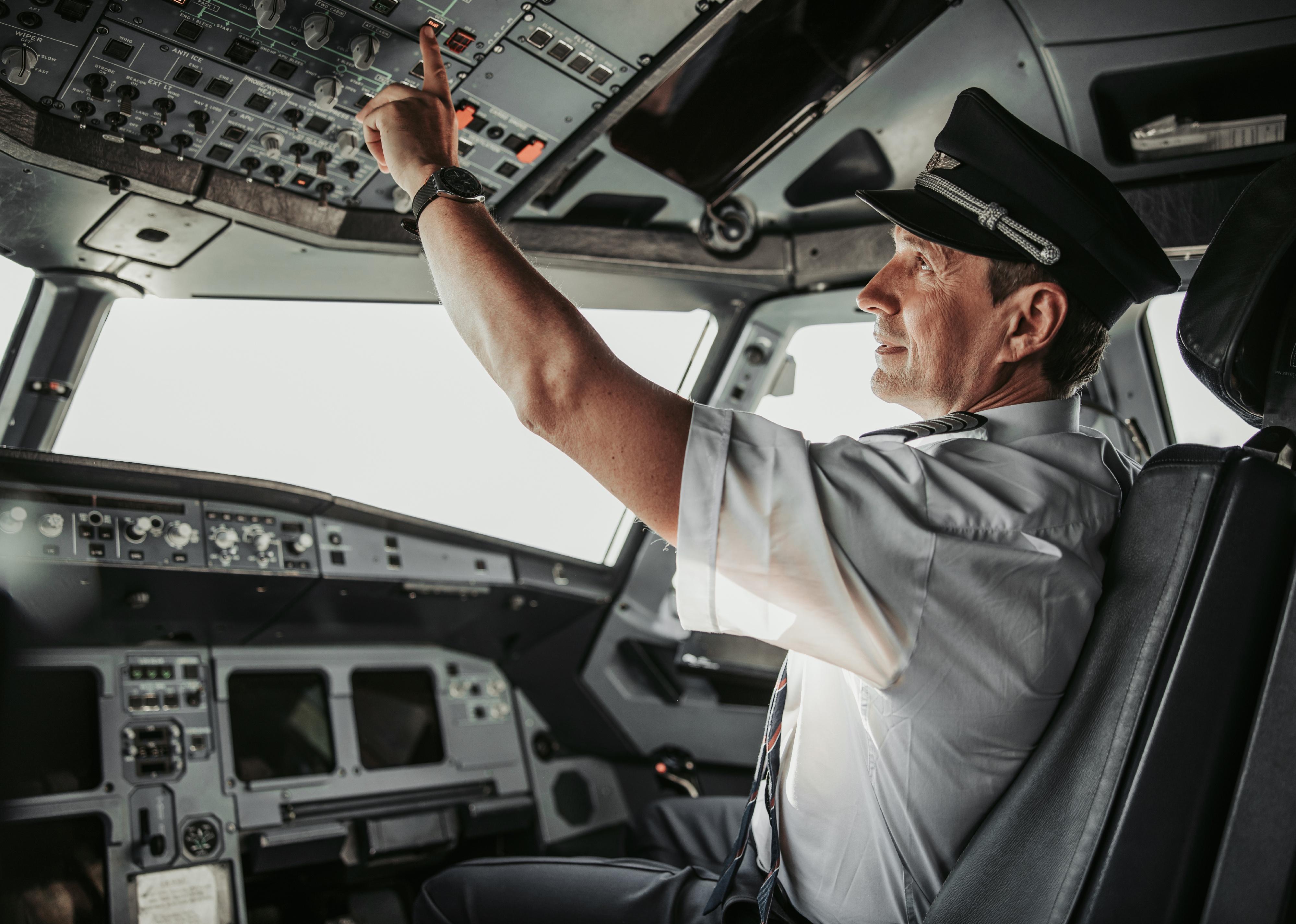Man in uniform pushing button in cabin during flight.