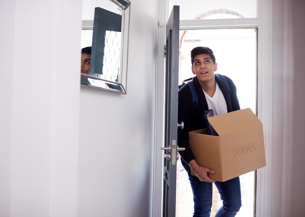 Young man entering room carrying a cardboard box