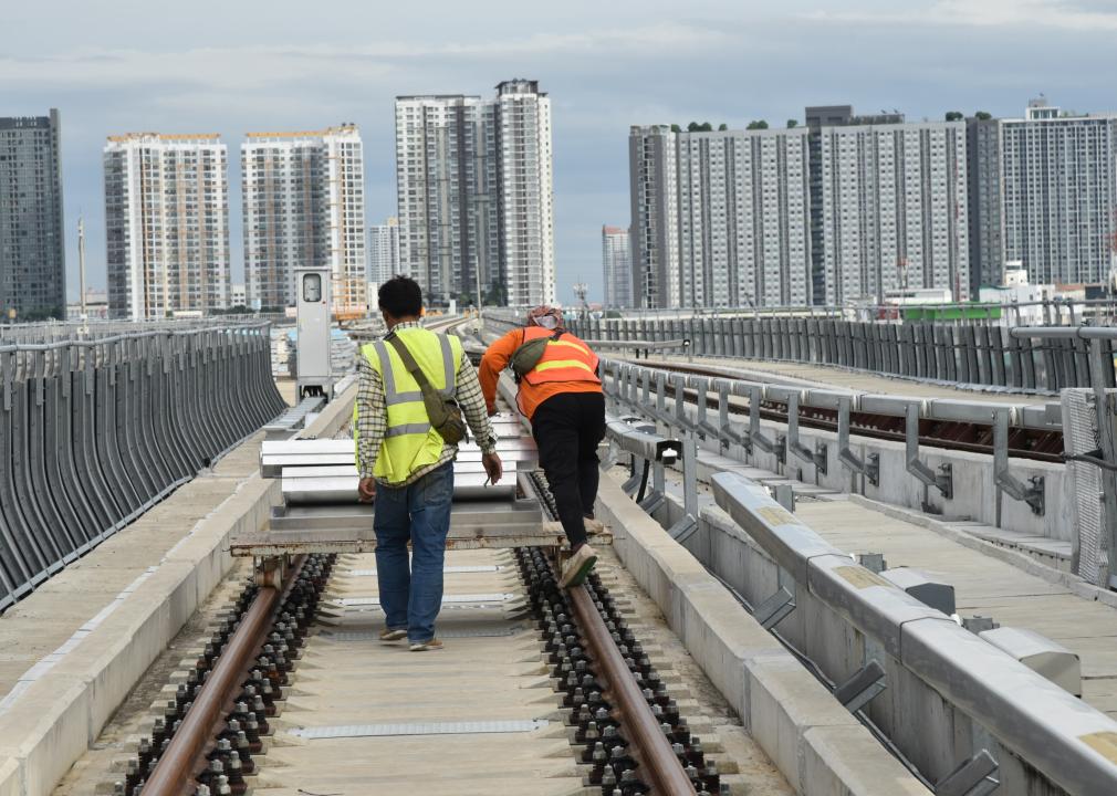 Workers moving equipment on a railway.