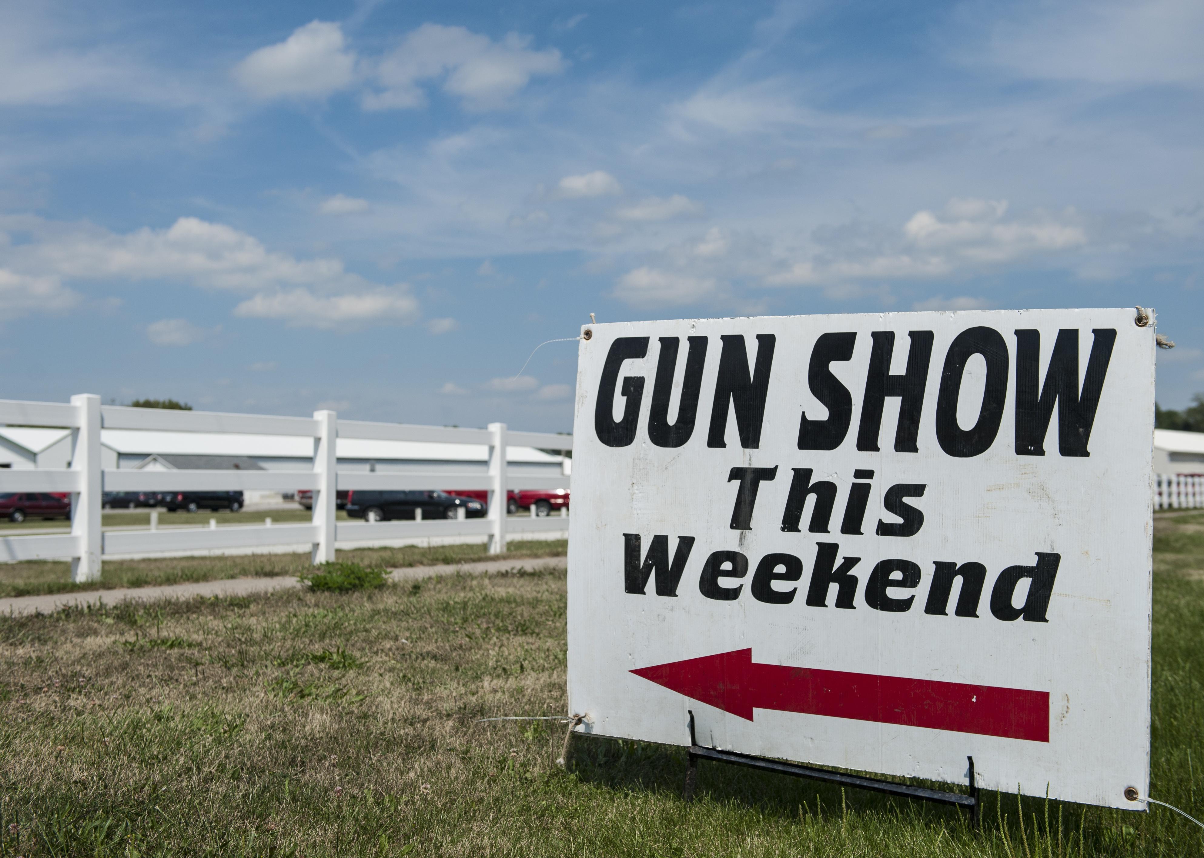 Gun show sign with an arrow outside.