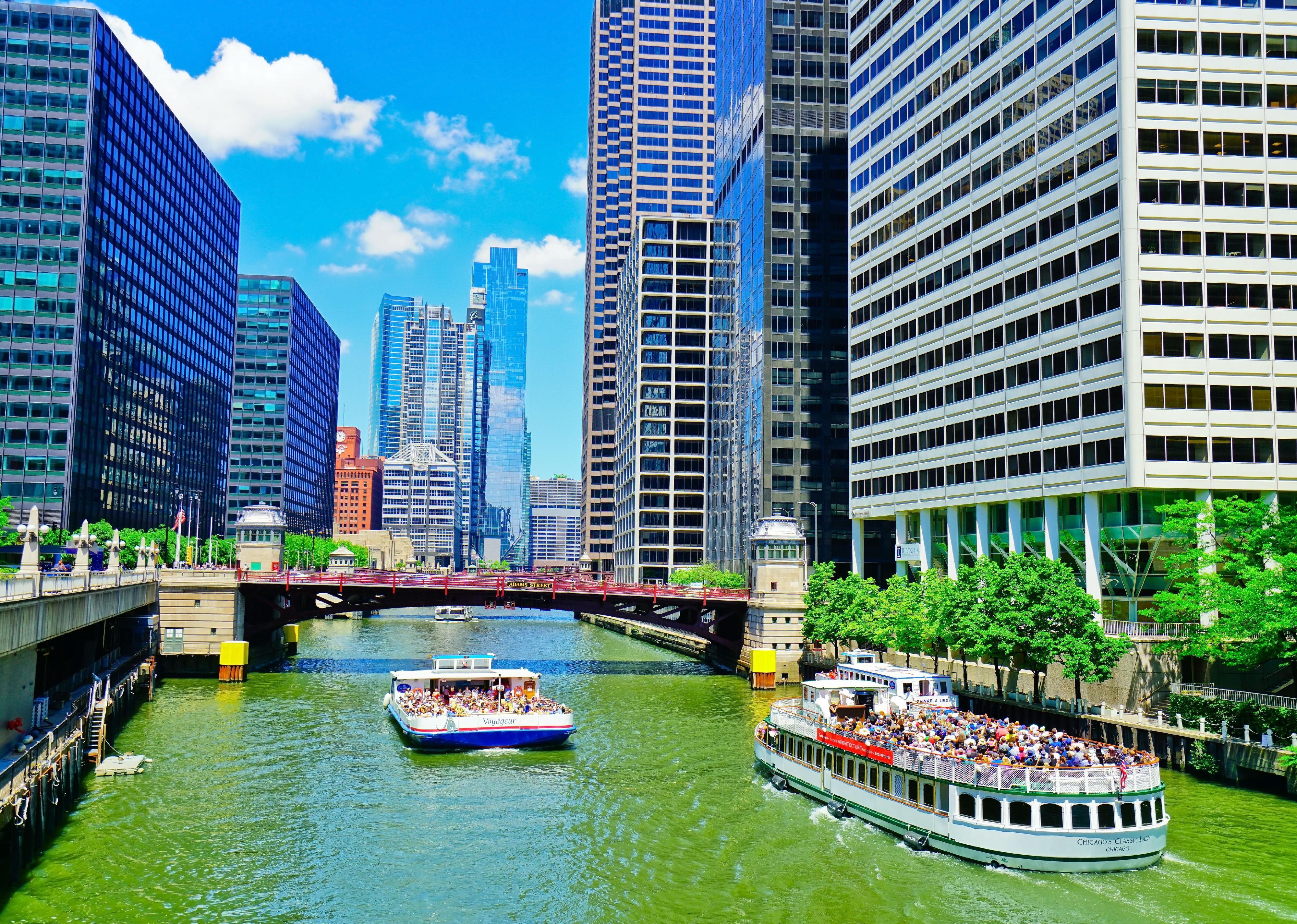 Two boats filled with people enjoy a day on the Chicago River.