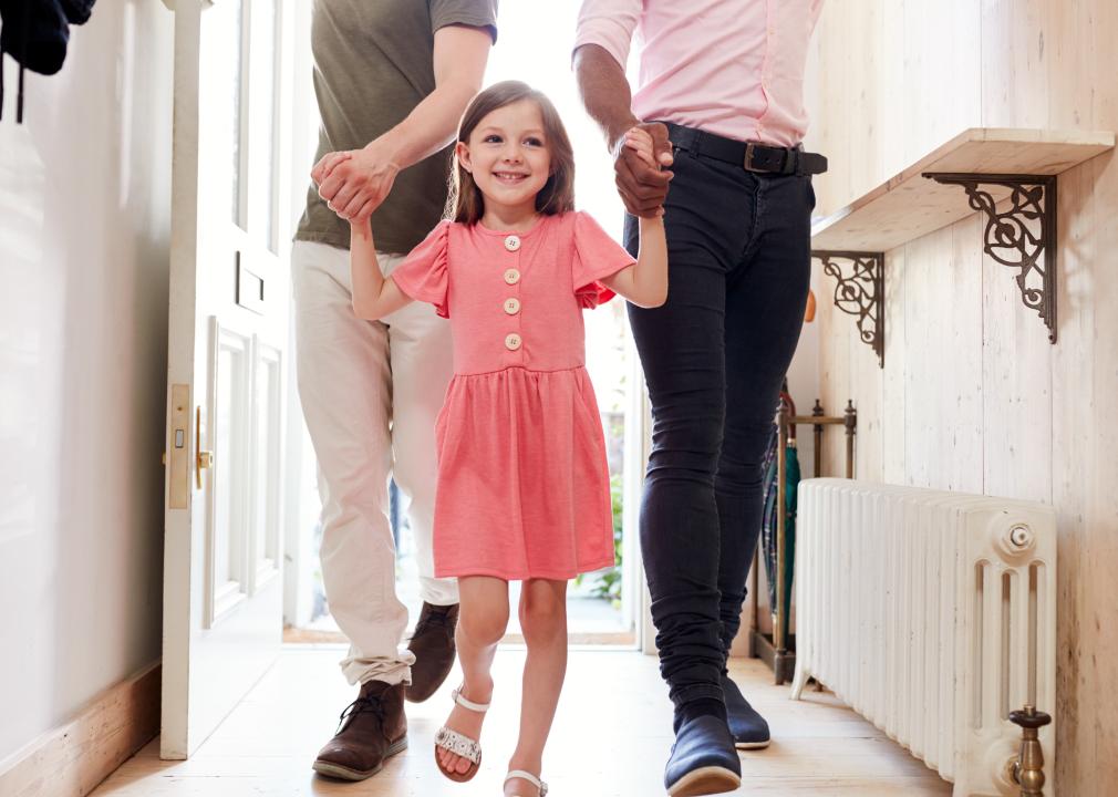 Close up of little girl holding hands of two men