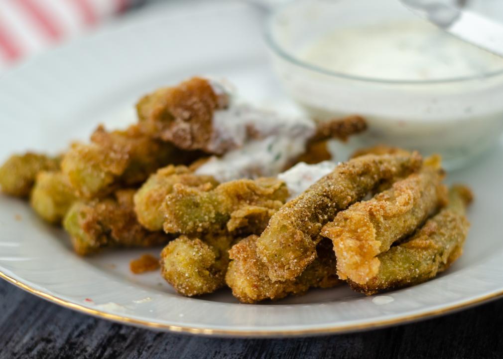 Crispy fried okra and spicy yogurt sauce on wooden table.