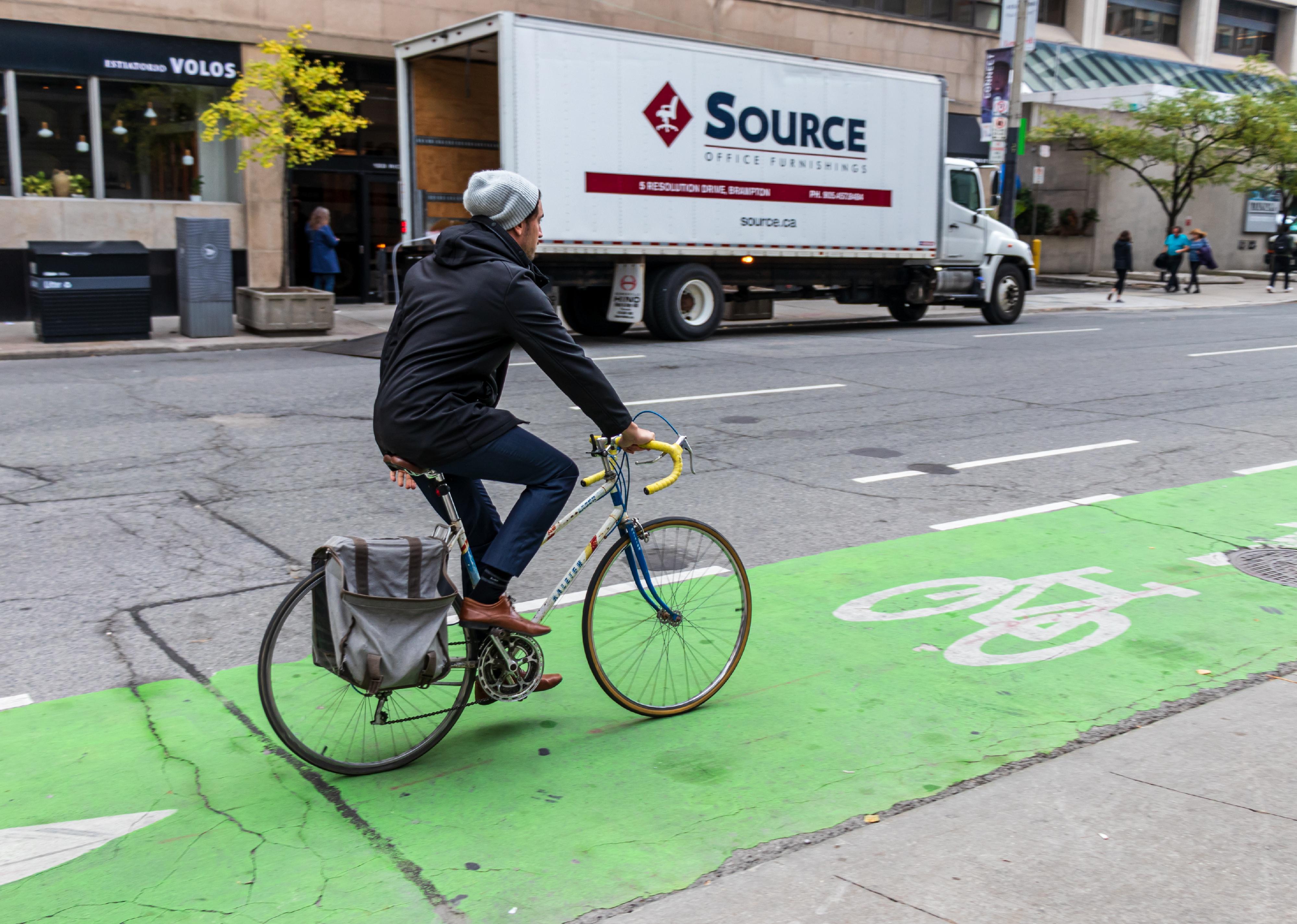 Man riding bike in green painted bike lane