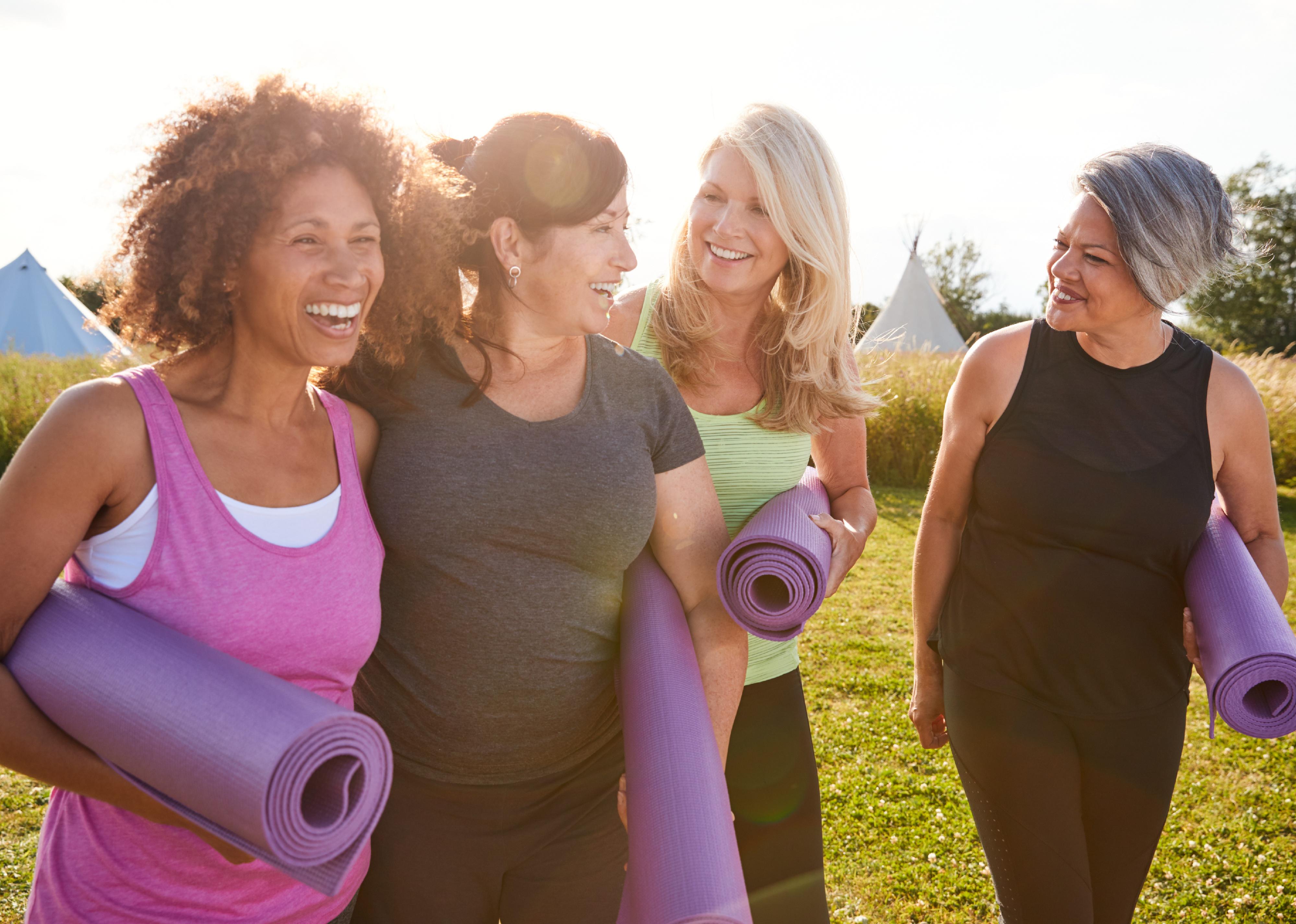 Group of mature women walking with yoga mats.
