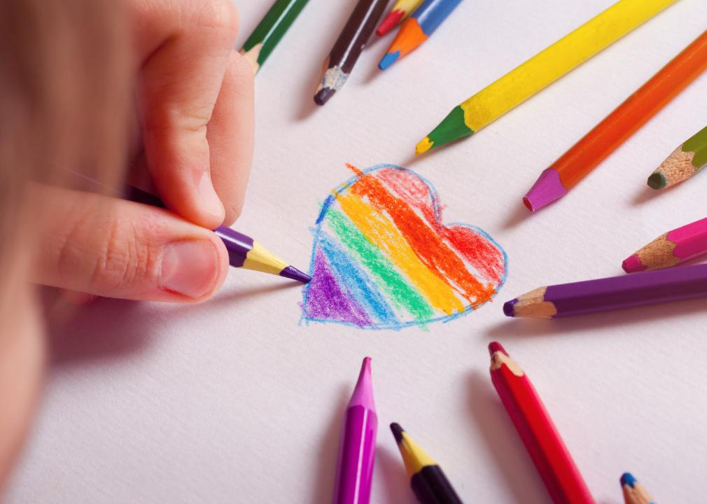 A little boy draws a heart colored in LGBT colors