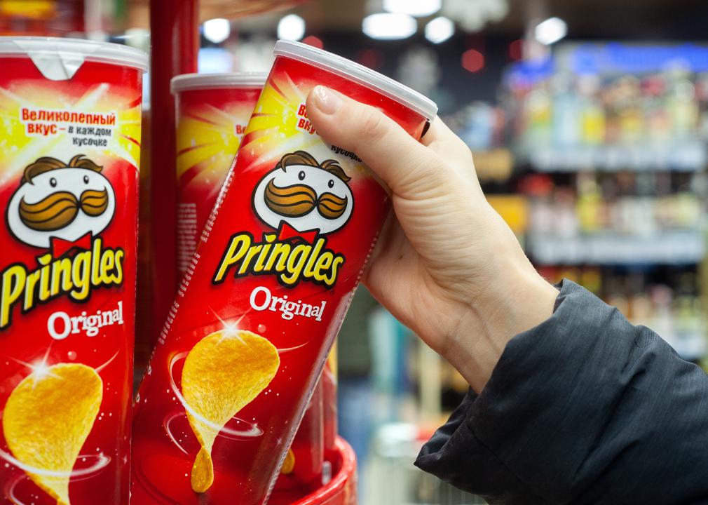 Hand hold a new tube of Pringles Potato Chips.