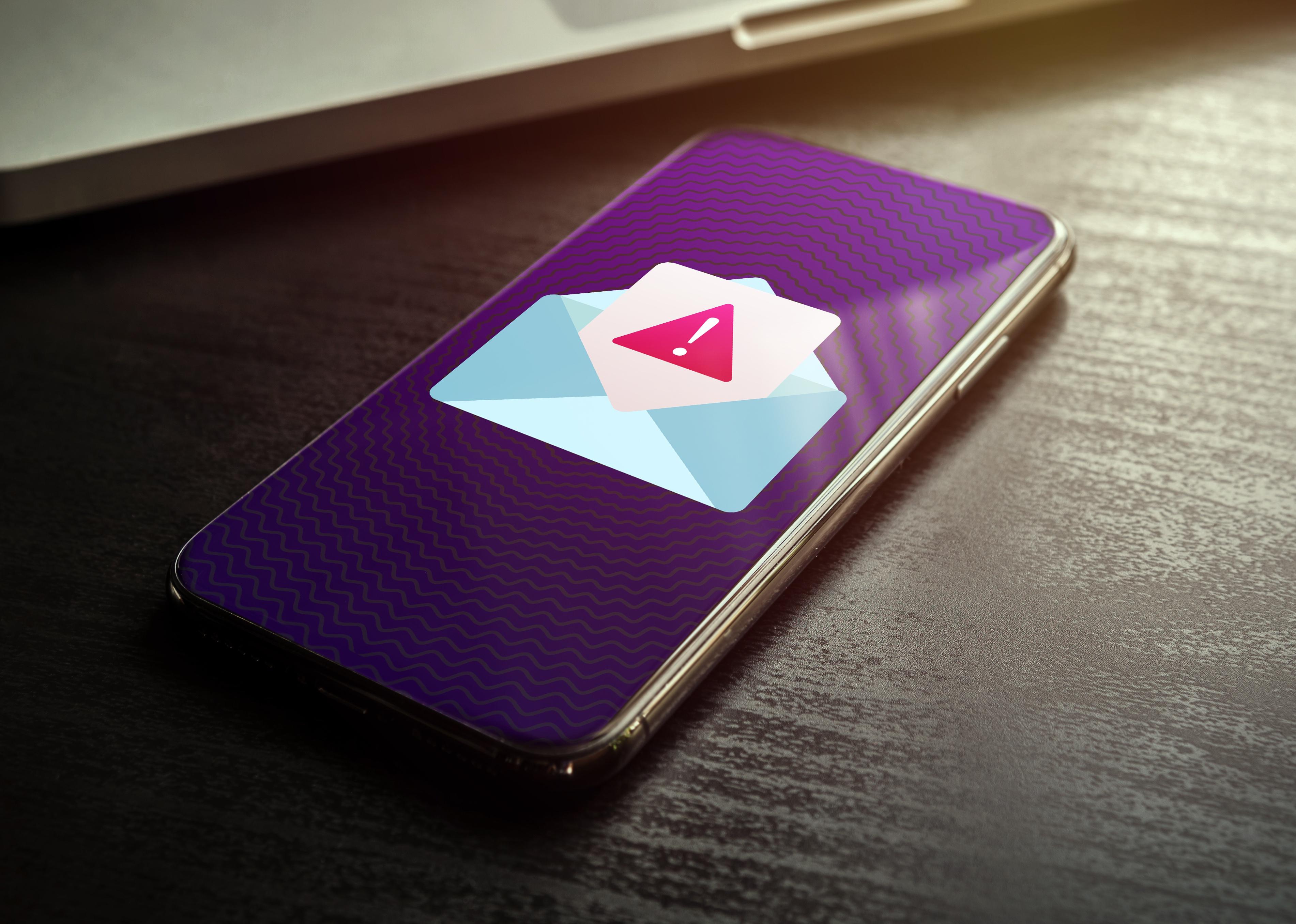 Smartphone with spam mail notification with alert and warning message icon.