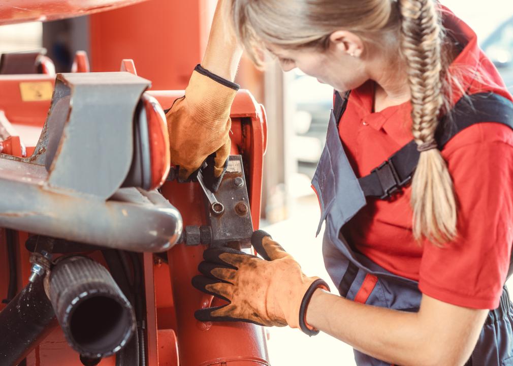 Female machinist working with a wrench on farm machinery