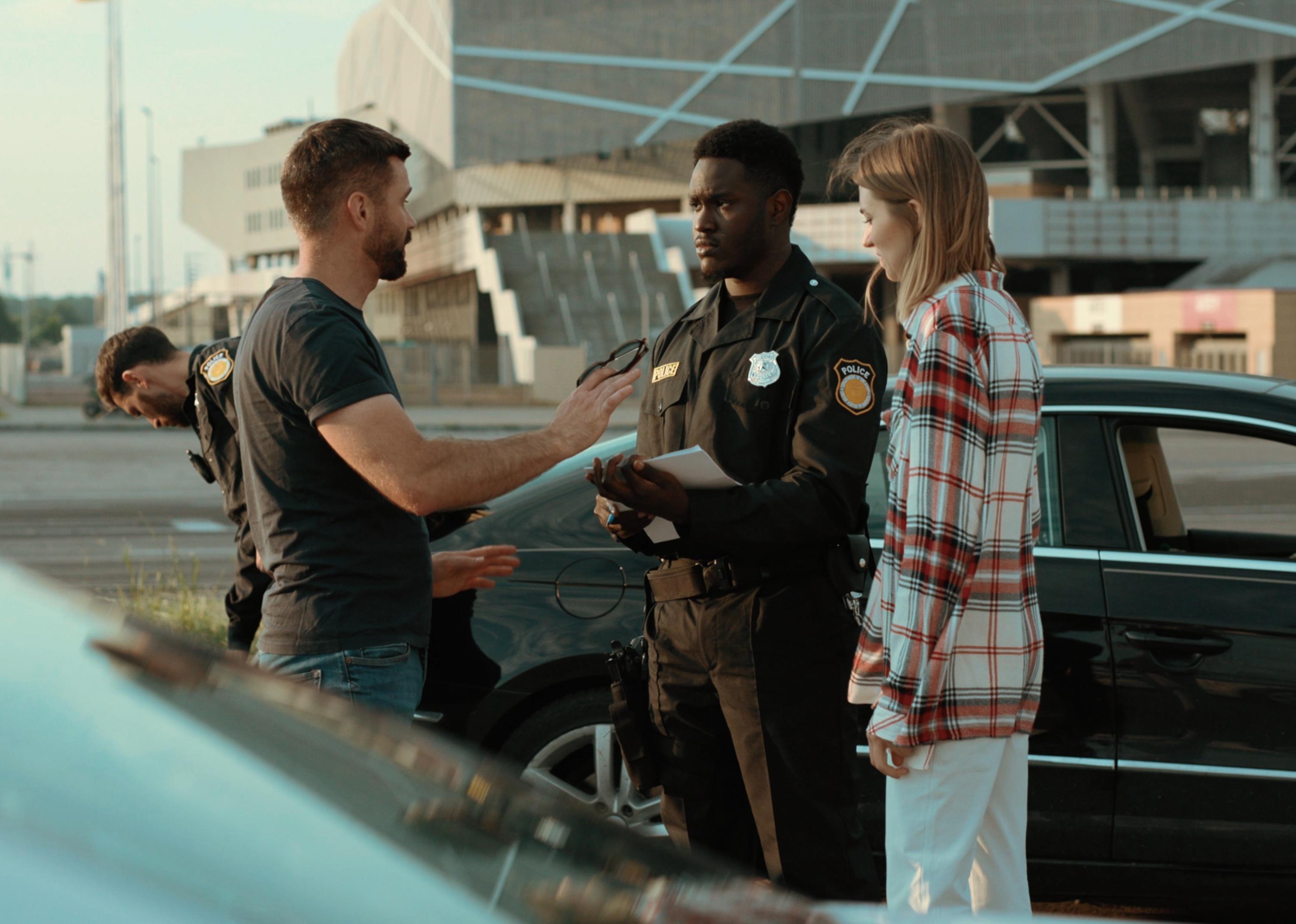 Two people talking with the police after a car accident.