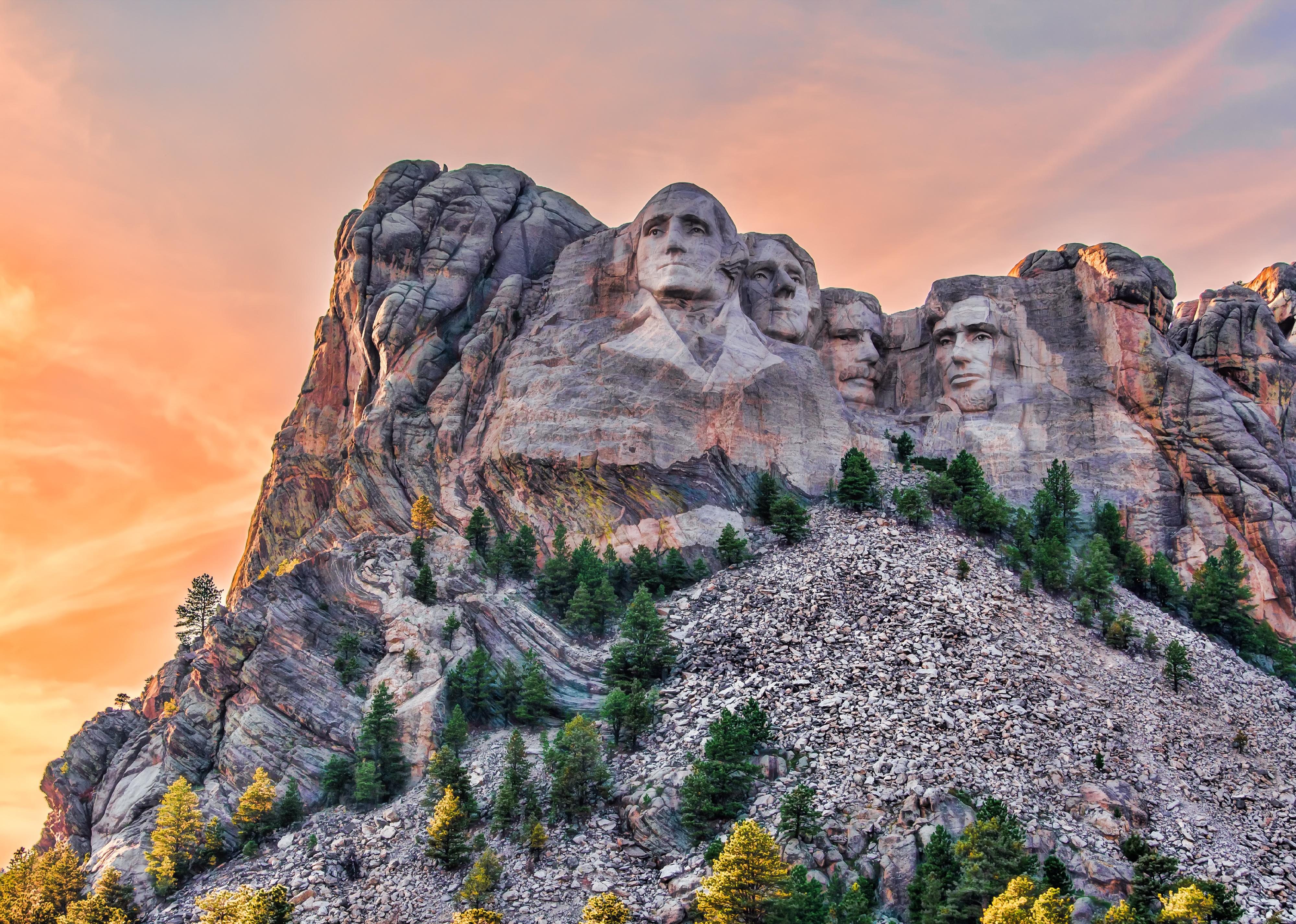 Mount Rushmore with colorful sunset in the background. 