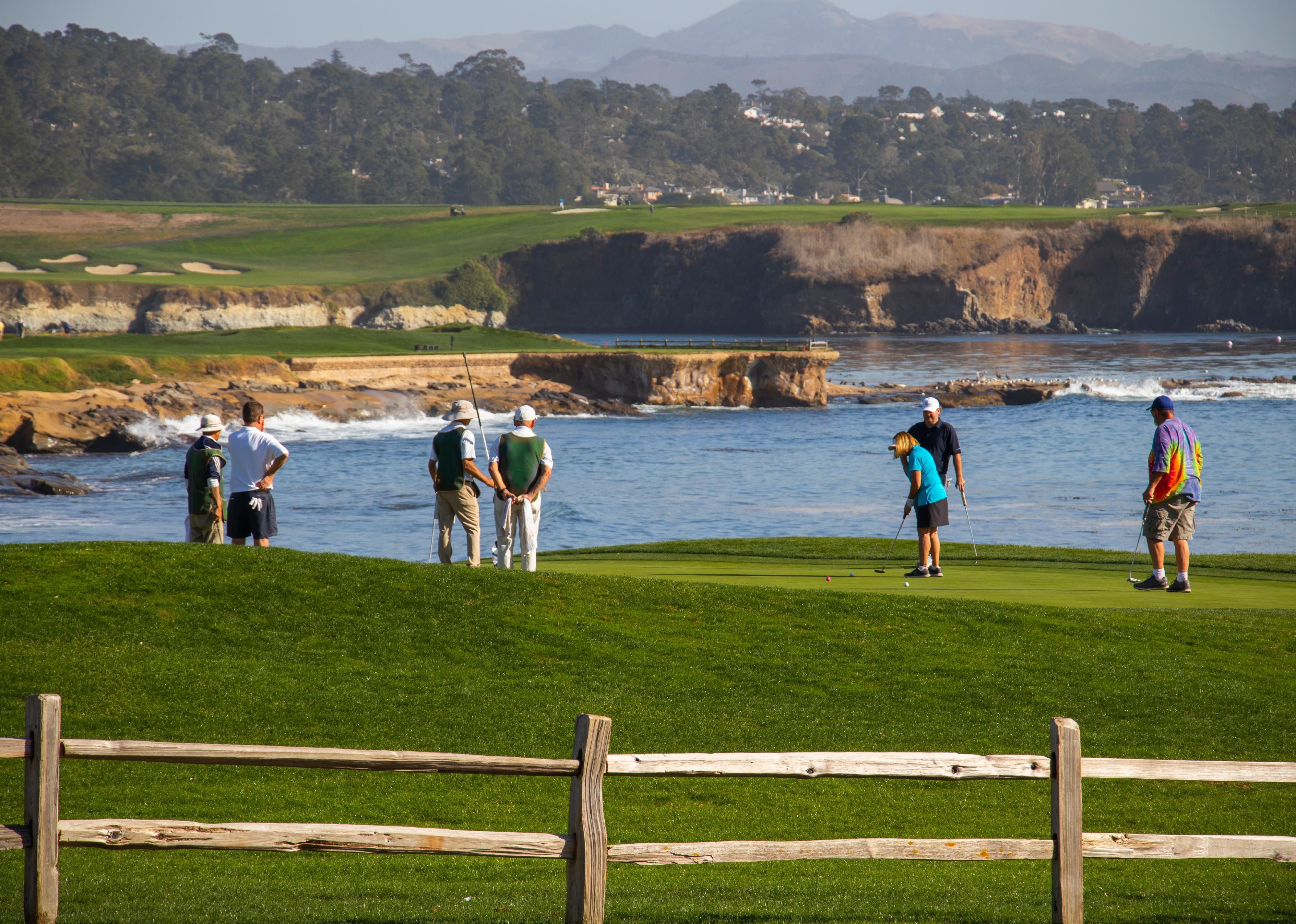 People playing golf on California coast.