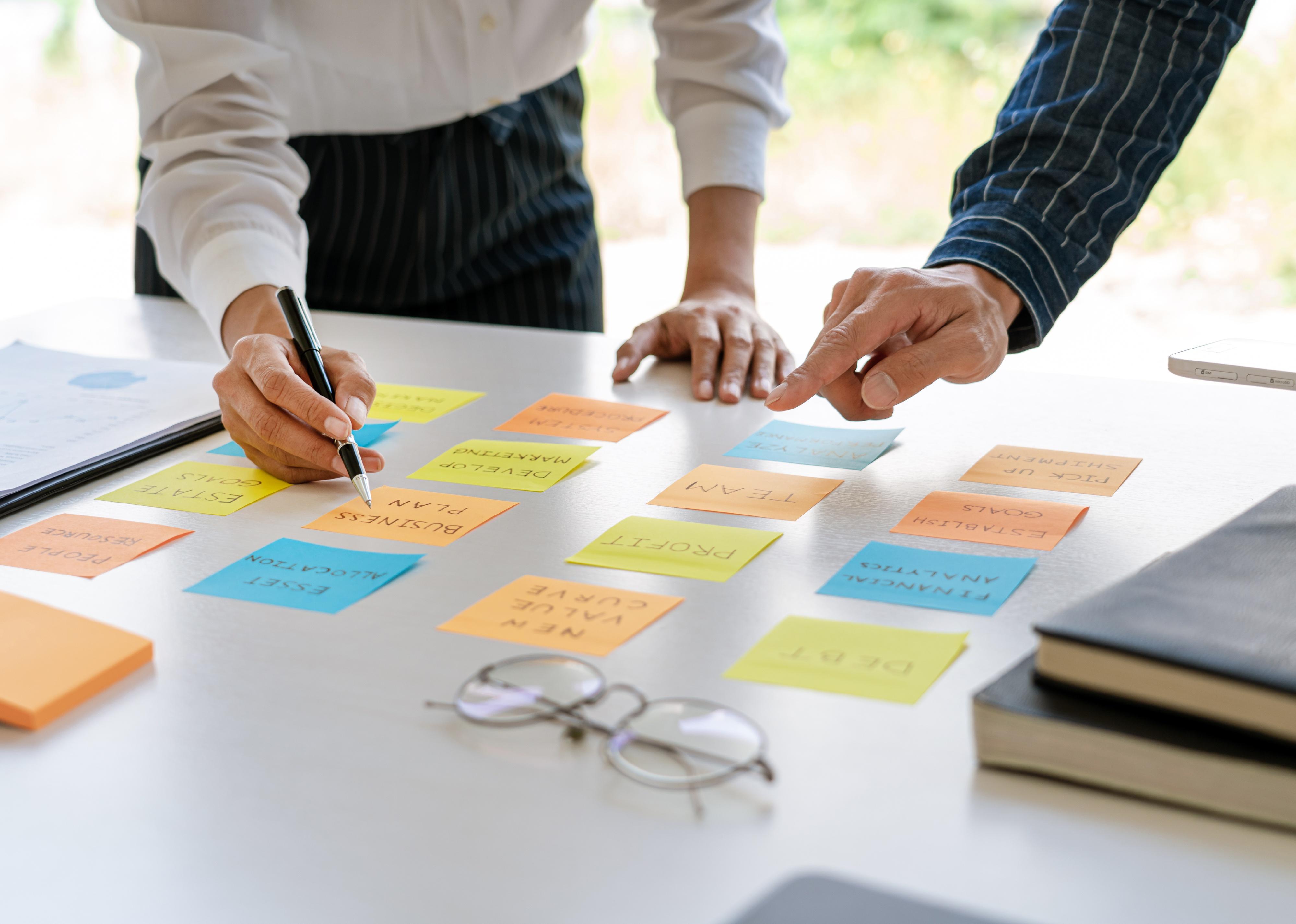 Businesspeople arranging sticky notes commenting and brainstorming.