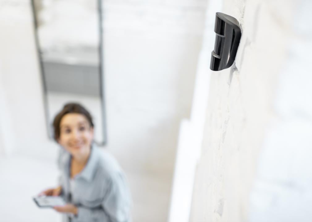 Woman standing in the room with motion sensor mounted on the wall