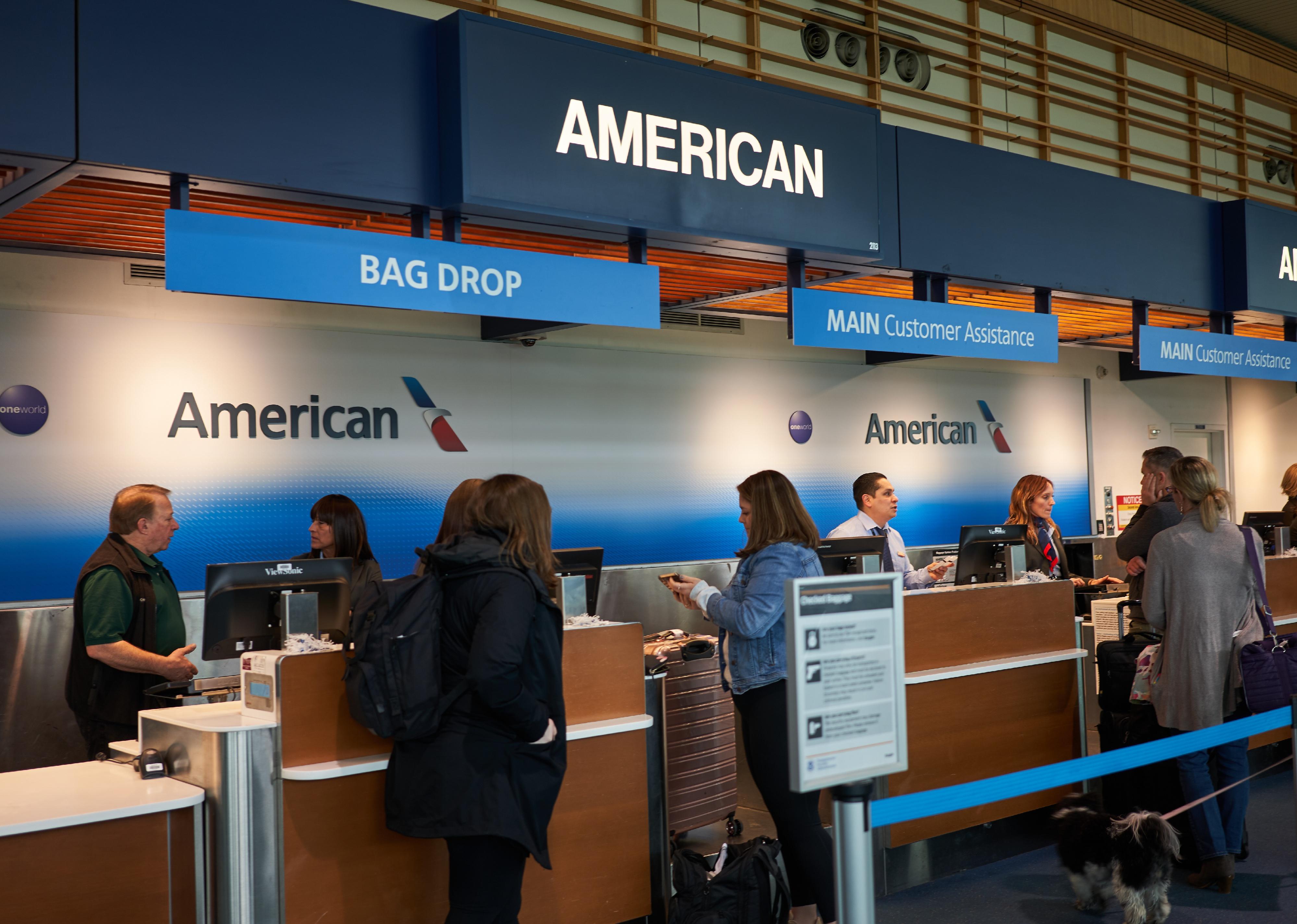 Passengers check their baggages at a American Airlines check-in desk