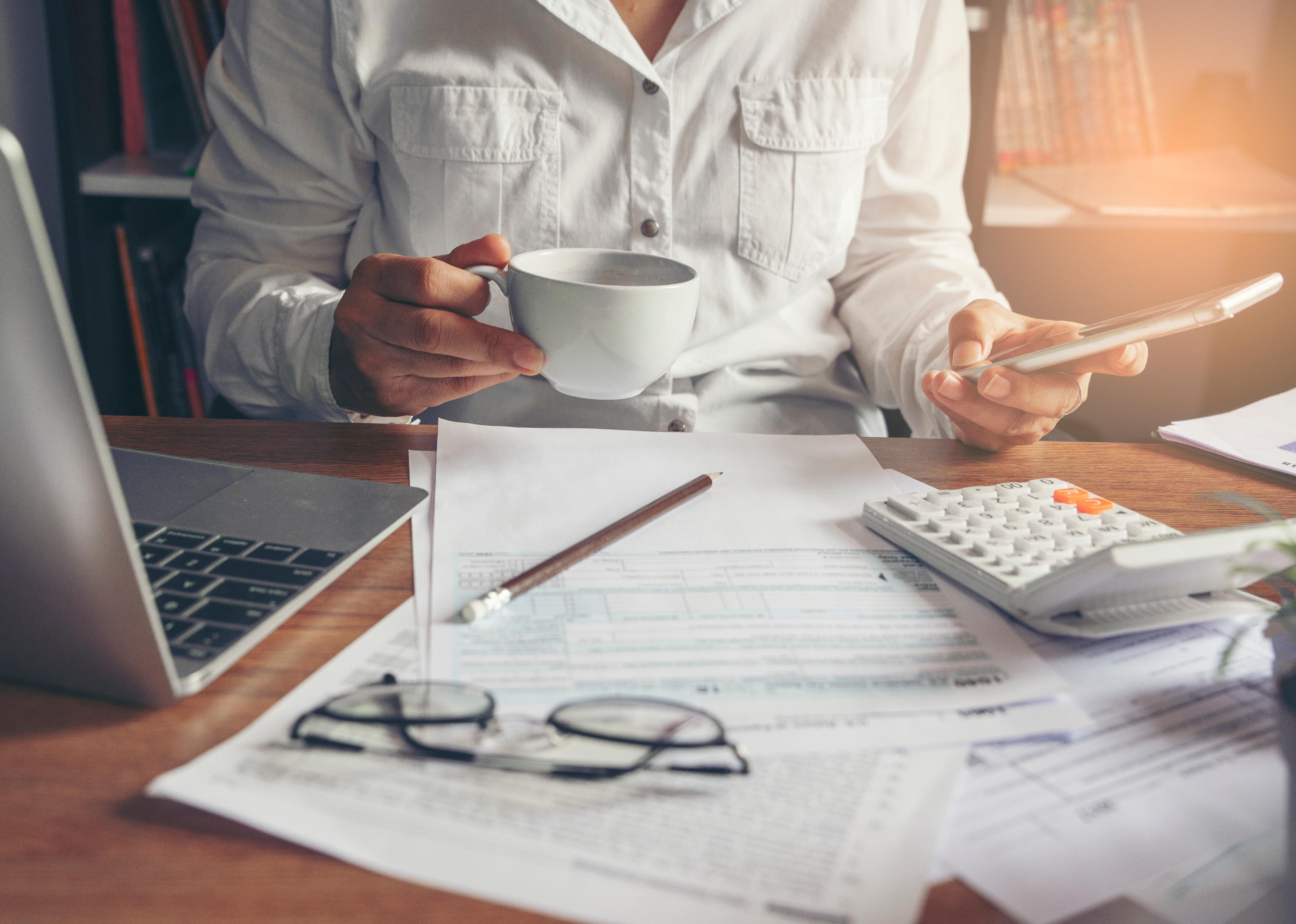 Accountant using smartphone calculating return tax.