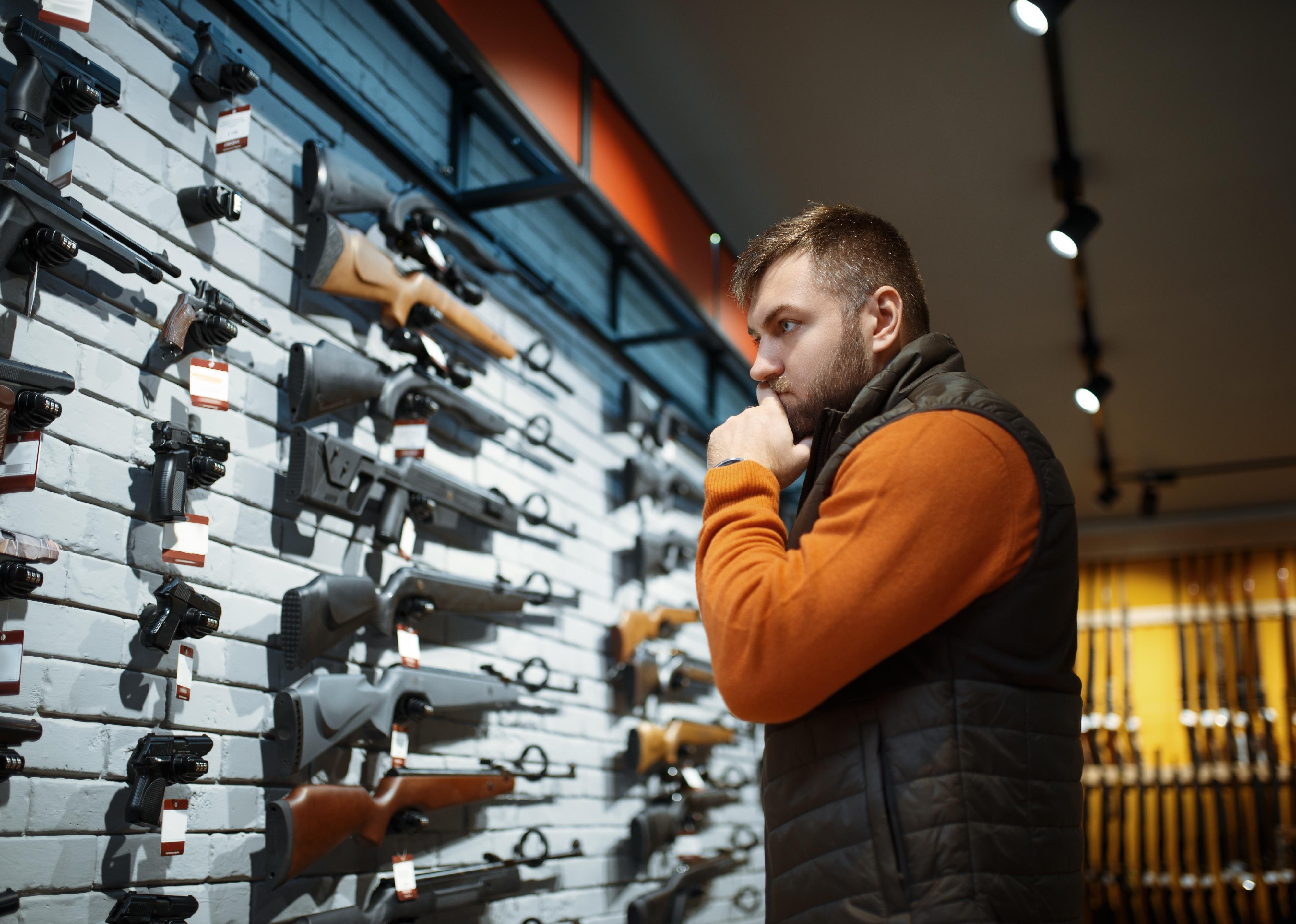 Person looking at a wall display of guns.